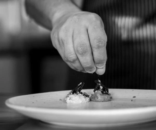 Une main salée en train de saupoudrer une assiette de nourriture avec du sel ou des épices.