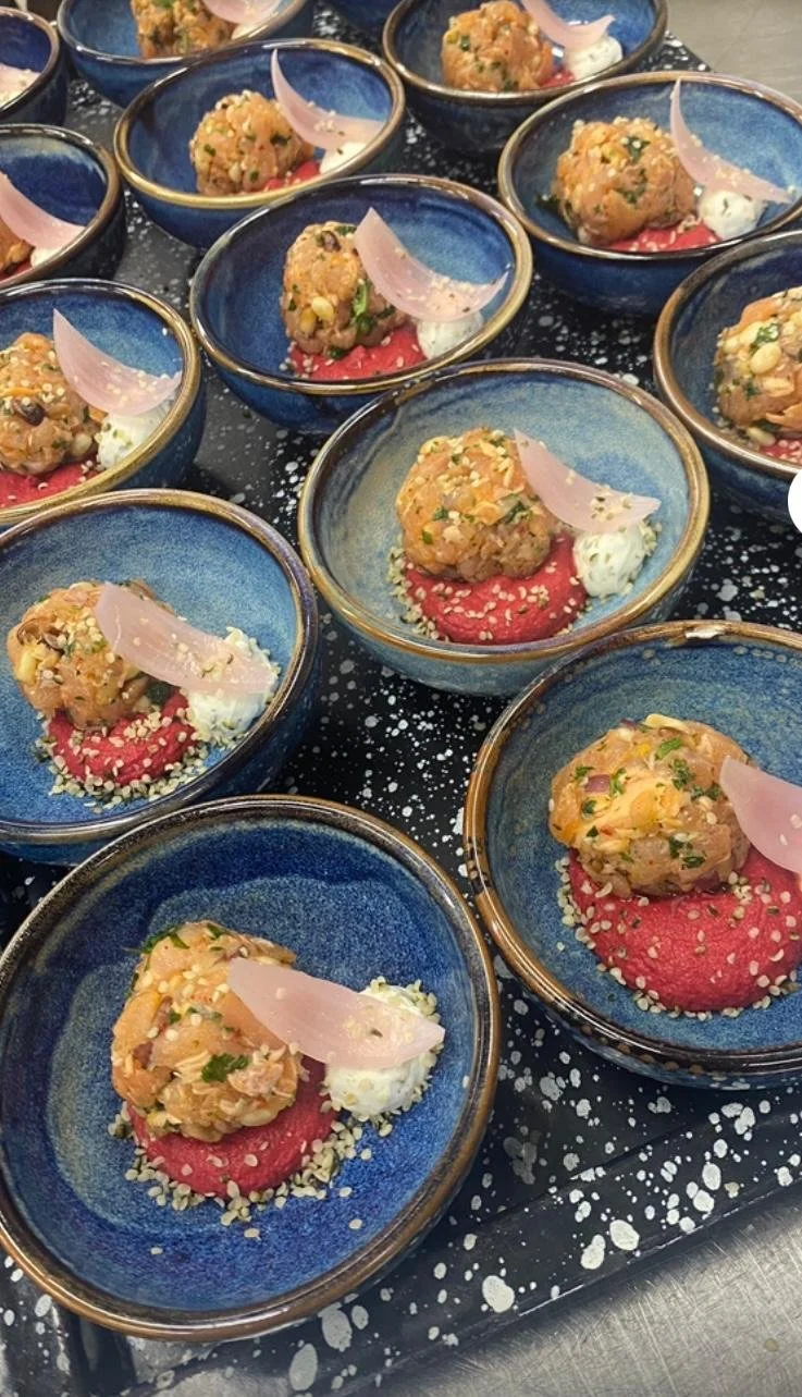 Petits bols en céramique bleue contenant des boulettes de viande ou poisson, servies sur une purée de betterave rouge, garnies de morceaux de légumes, de graines et de fines tranches d'oignon ou de radis.