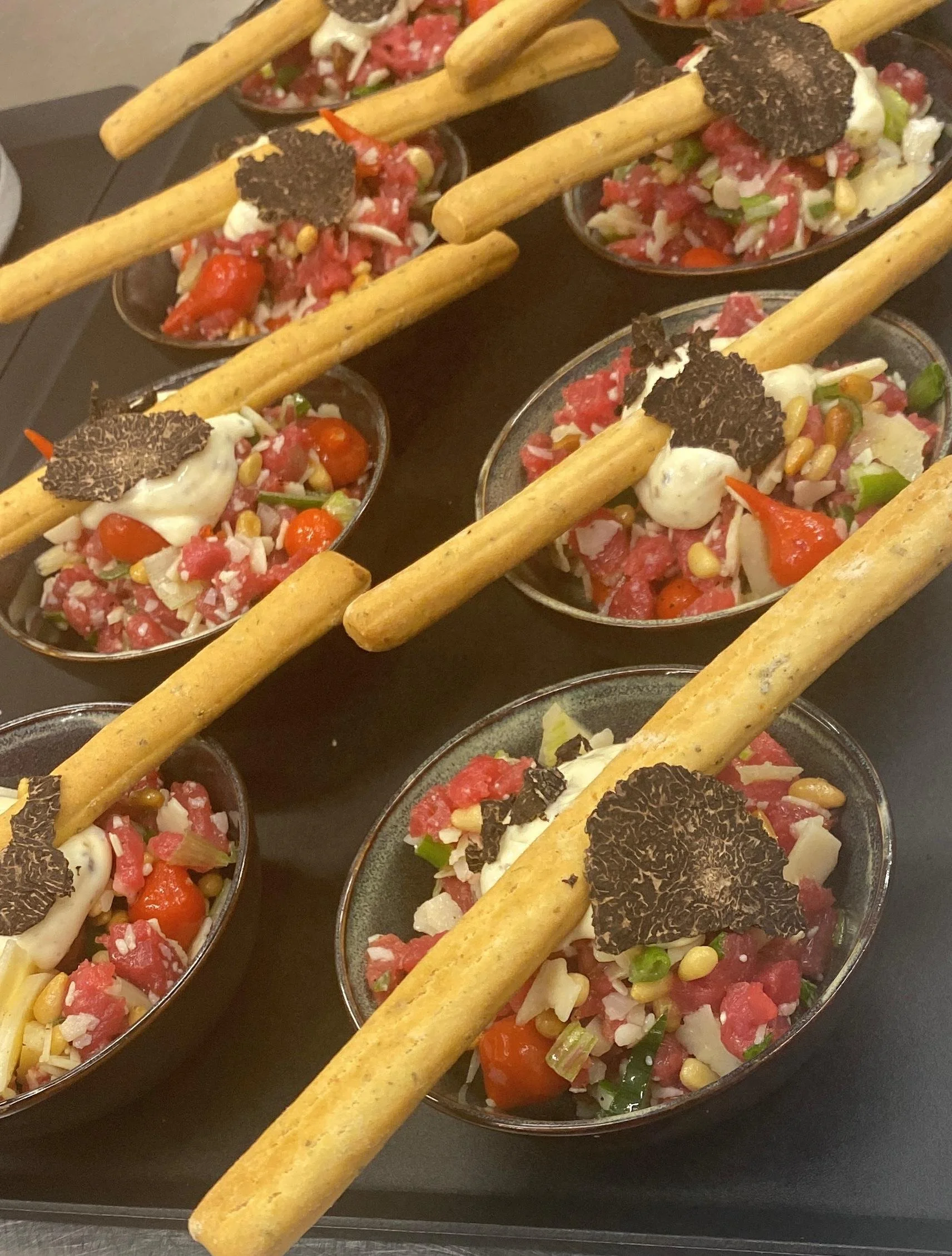 Coupes de ceviche avec des tortillas de maïs sur un plateau noir.