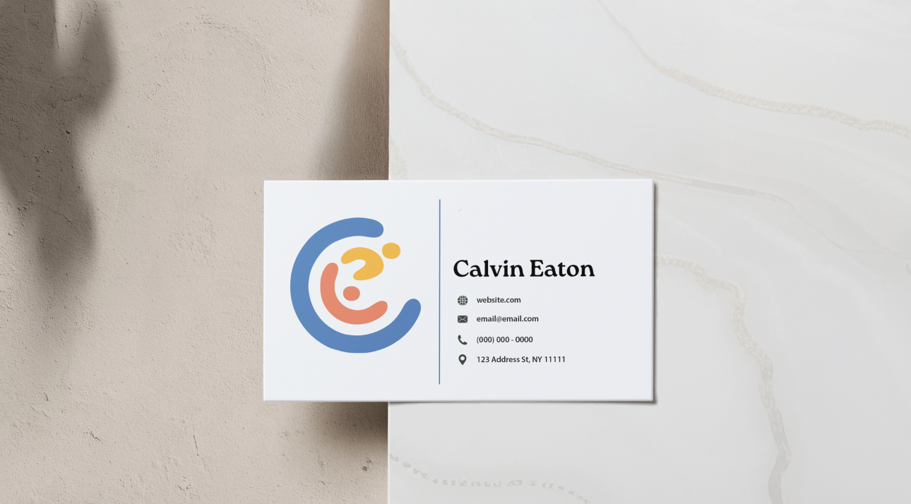 Business name and contact information on a white card with a colorful logo, placed on a marble and beige wall background.