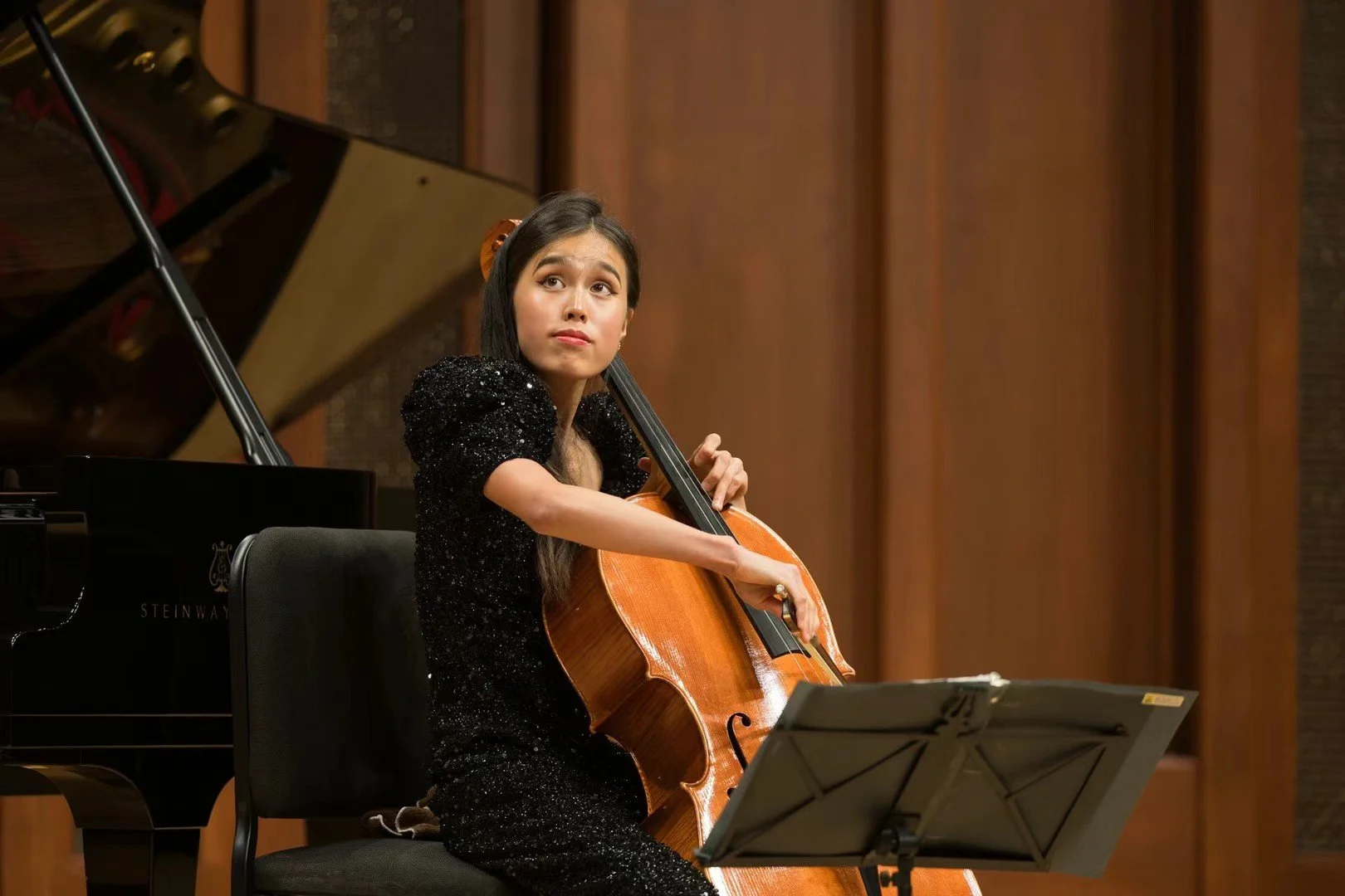 Young woman playing the cello during a performance in a concert hall.