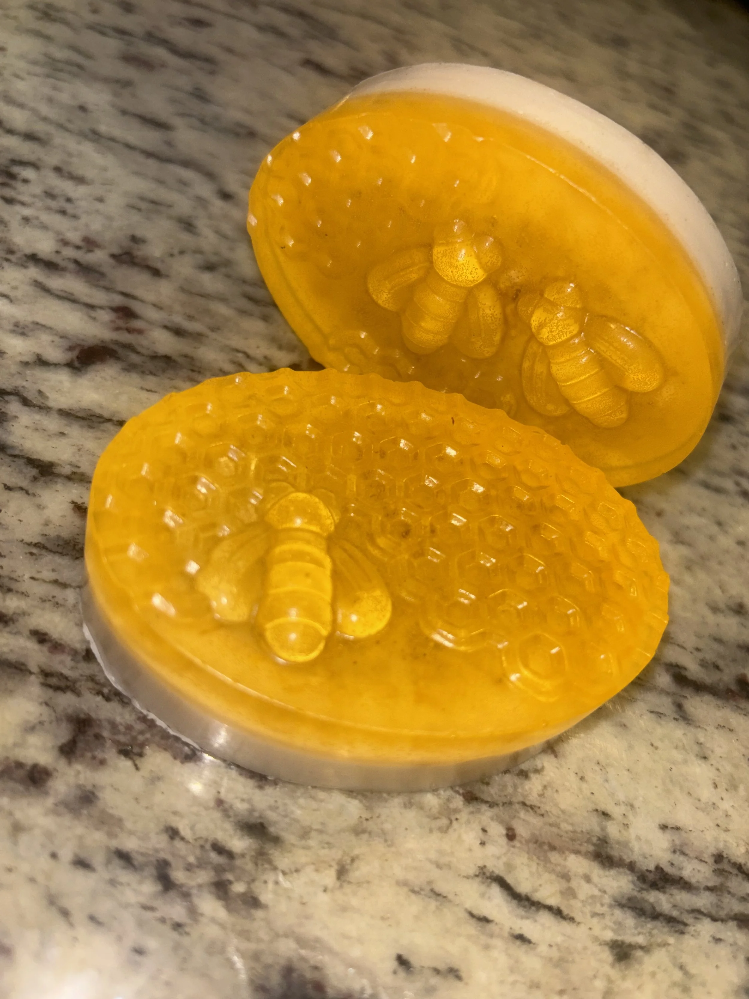Close-up of a yellow candy in a clear container, placed on a speckled granite countertop.