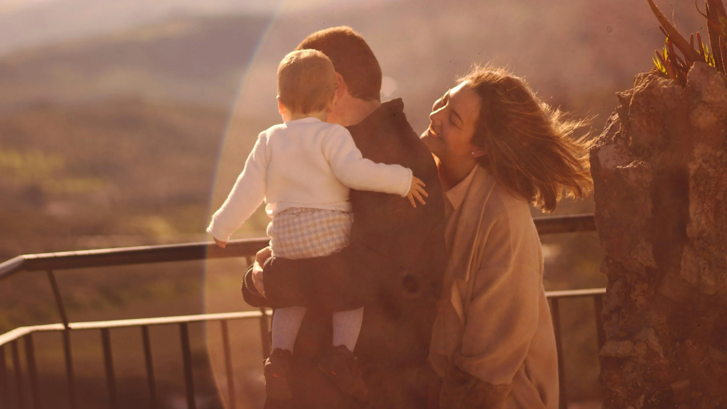 A family enjoying a moment outdoors with a rainbow visible in the background.