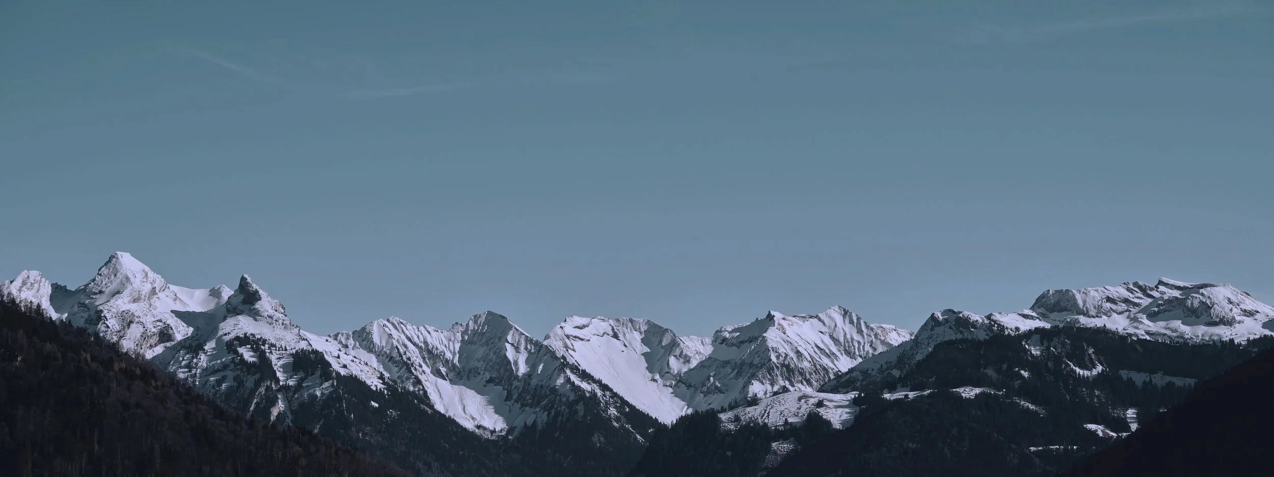 Snow-covered mountain range under a clear blue sky.