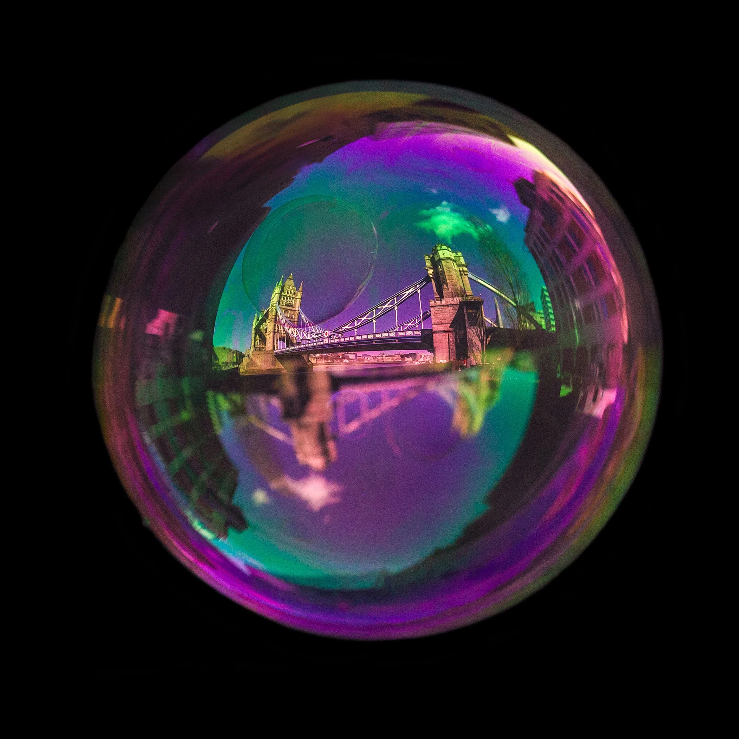 Real soap bubble reflecting London tower bridge photographed against a black background