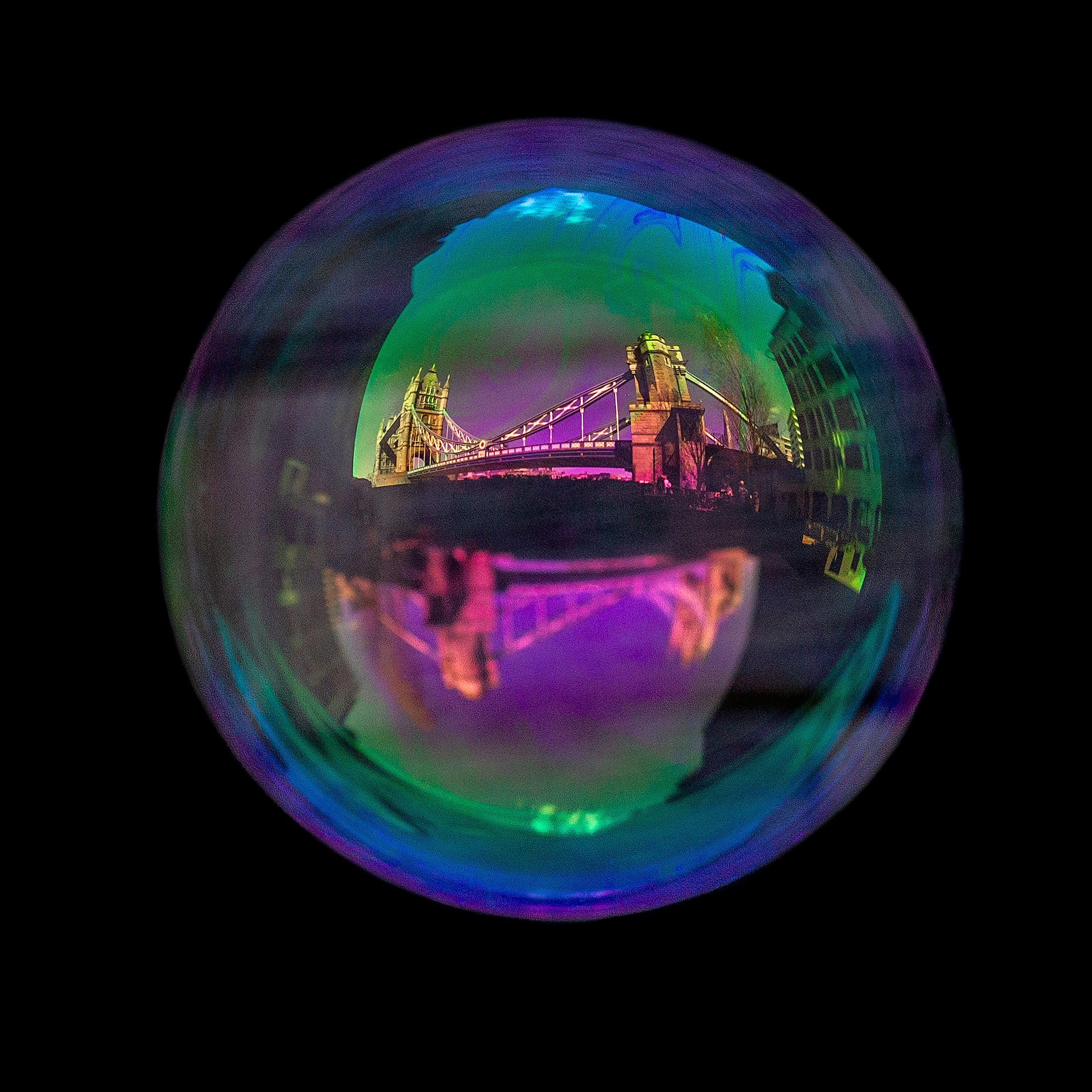 Real soap bubble reflecting London tower bridge photographed against a black background