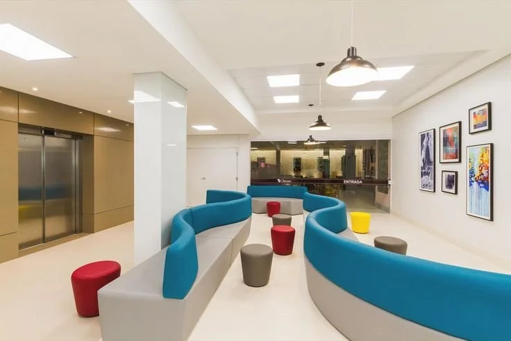 JC Trades Services LLC. Modern waiting area with colorful curved benches, small round stools, and framed artwork on white walls.