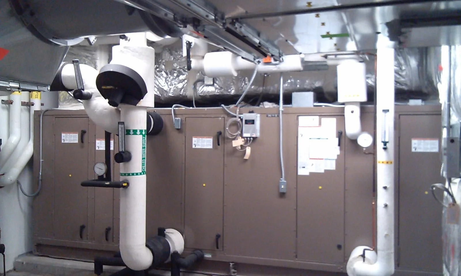 Industrial mechanical room with pipes, valves, gauges, and electrical panels.