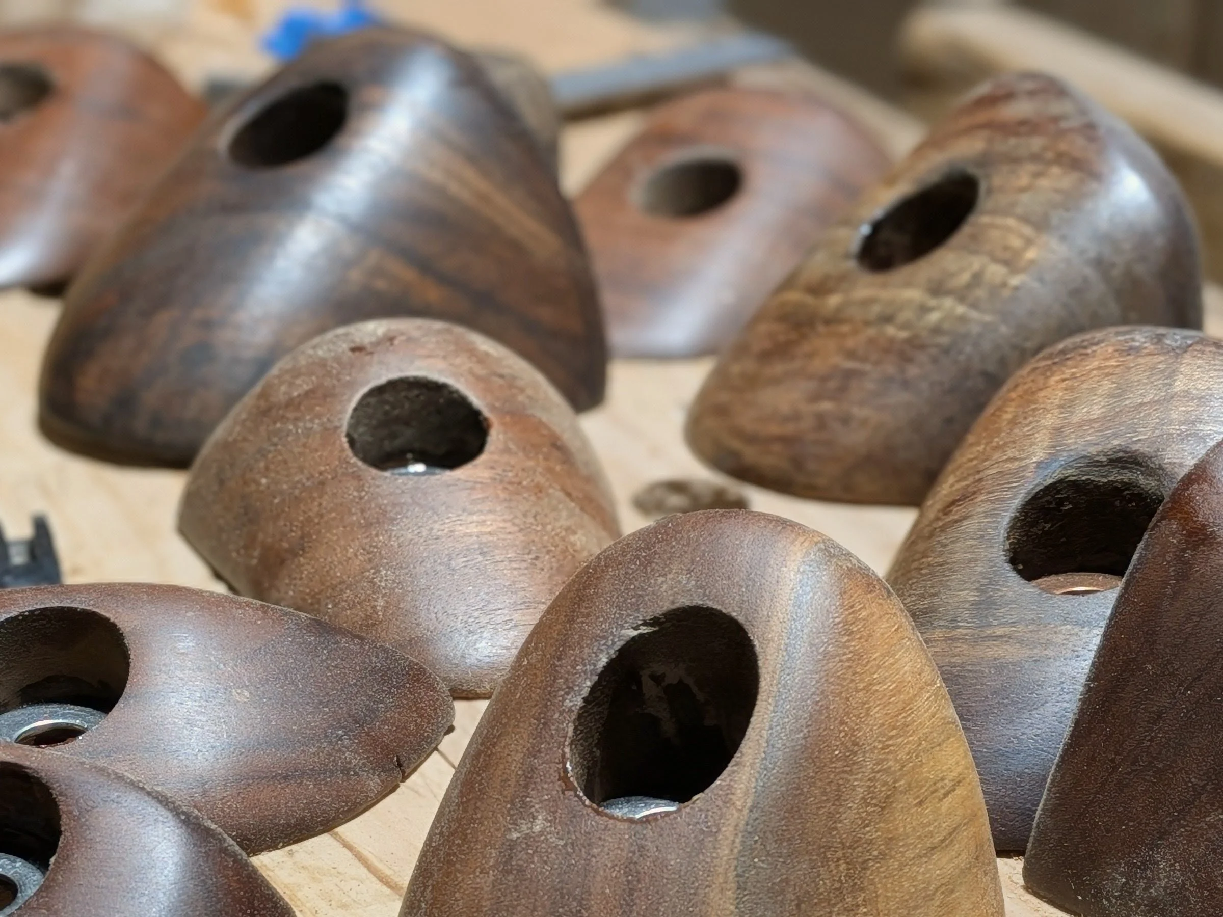 Close-up of several rusted, hollow, conical metal objects with large holes at the wider end, arranged on a wooden surface.