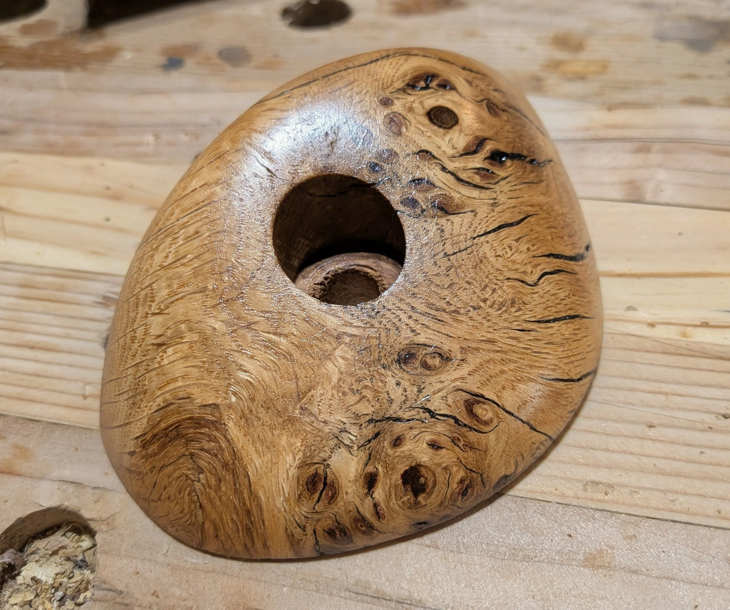 Close-up of a wooden birdhouse with a round entrance hole, resting on a wooden surface.