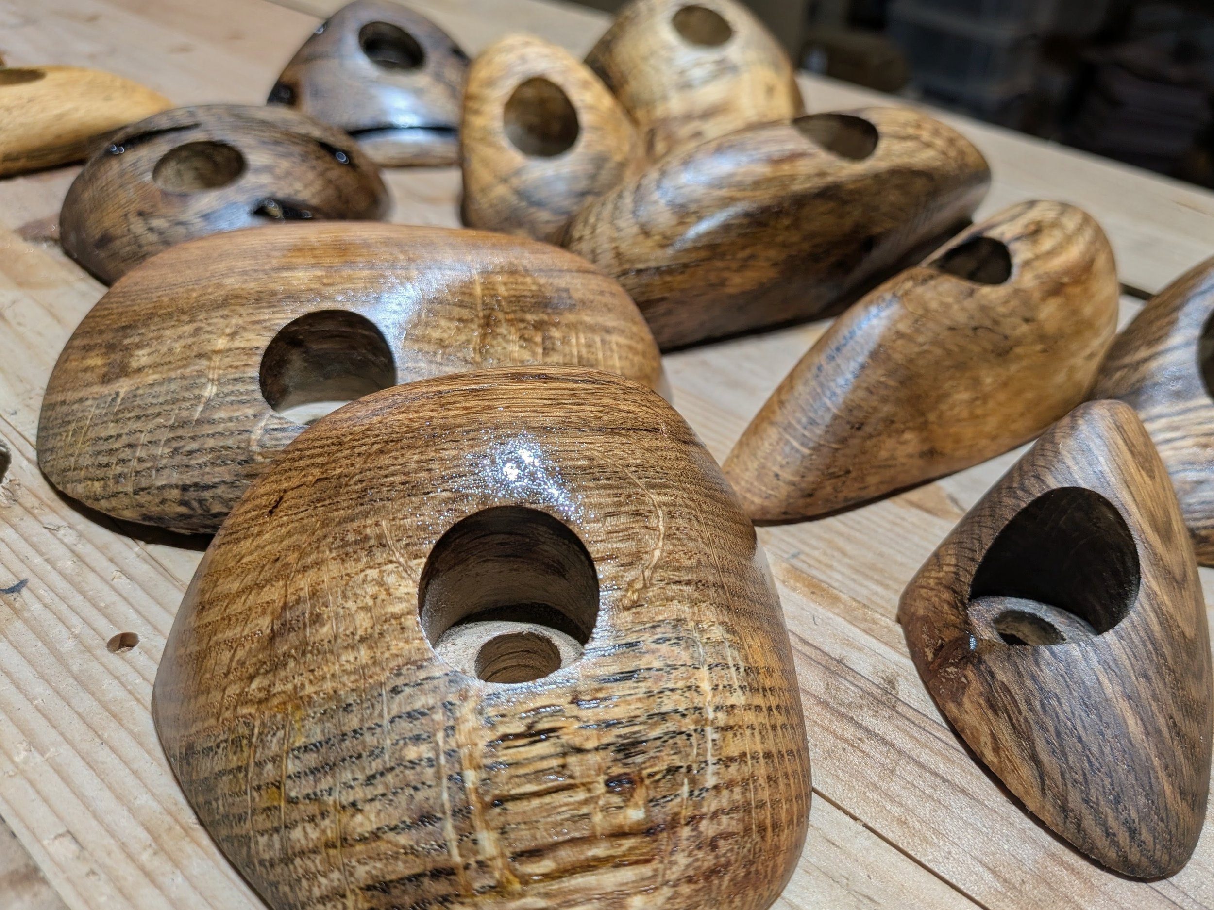 A collection of wooden objects, each with an oval hole in the center, resting on a wooden surface.
