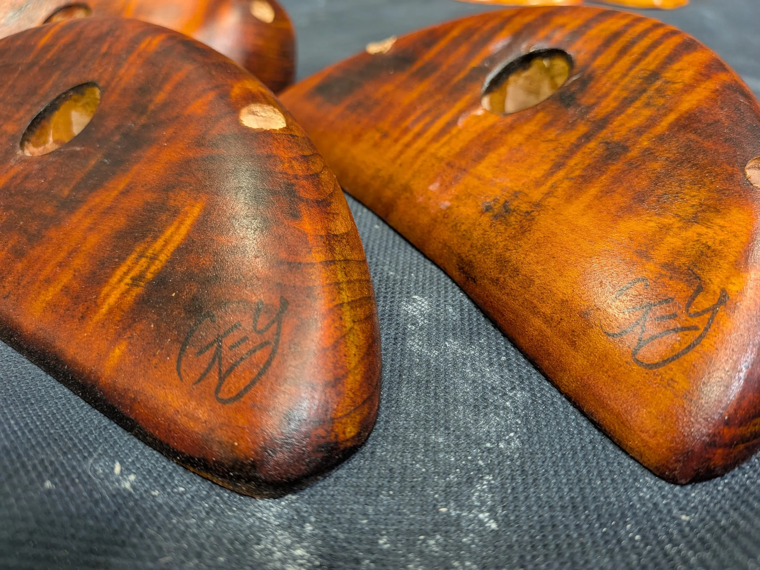 Close-up of several wooden gumball or toy capsules with marbled brown and orange patterns on a dark textured surface.
