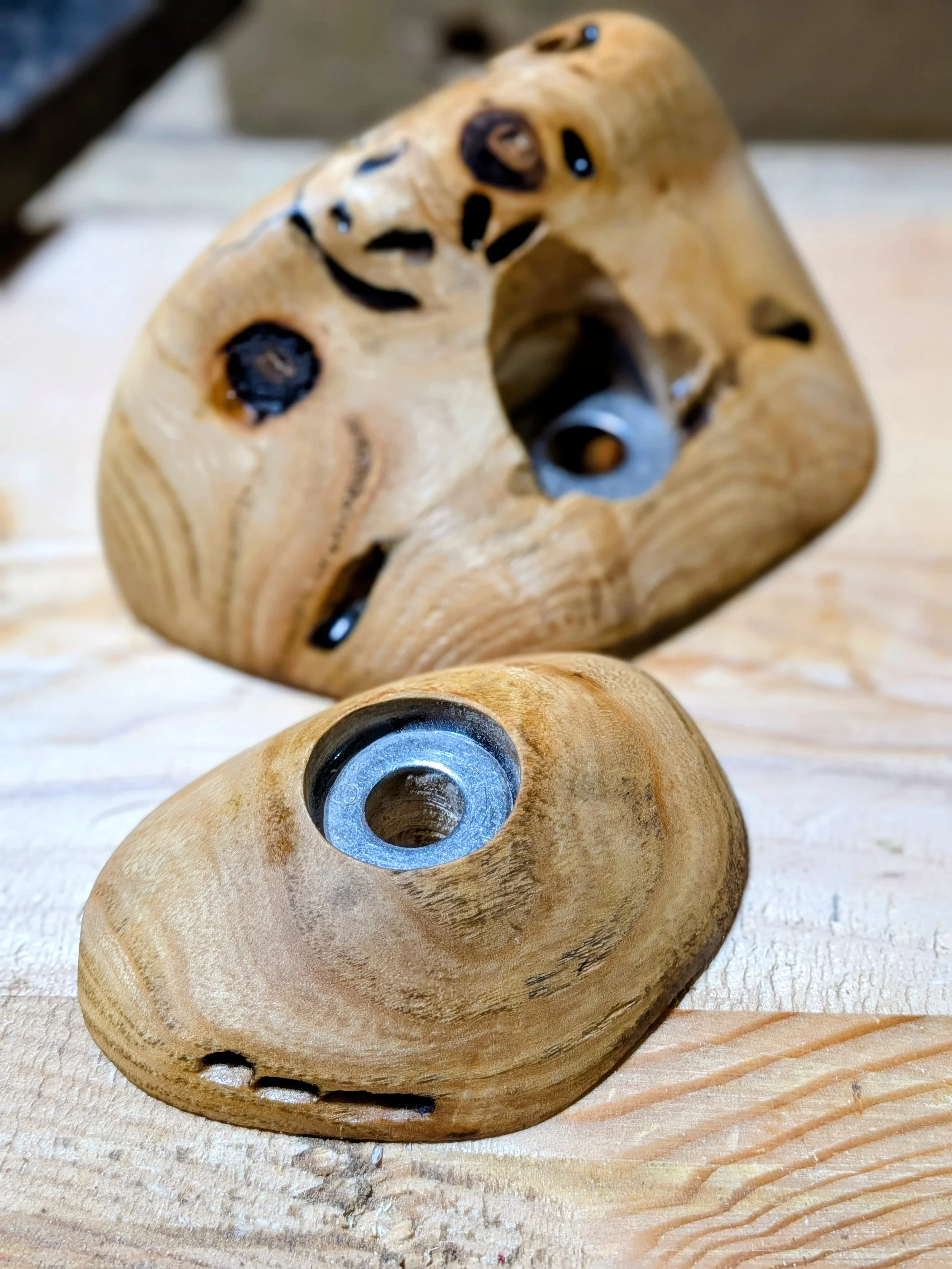 Close-up of a wooden figurine shaped like a horse's head with black painted eyes, resting on a wooden surface.