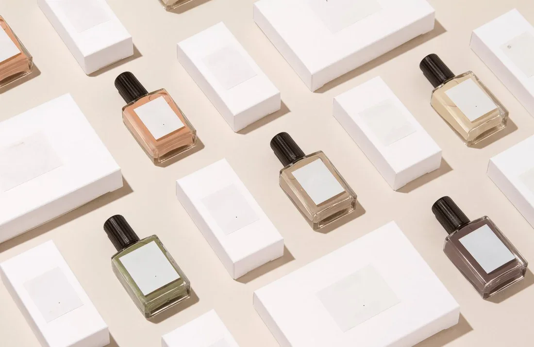 Display of perfume bottles and boxes on a beige surface, arranged in a grid pattern.
