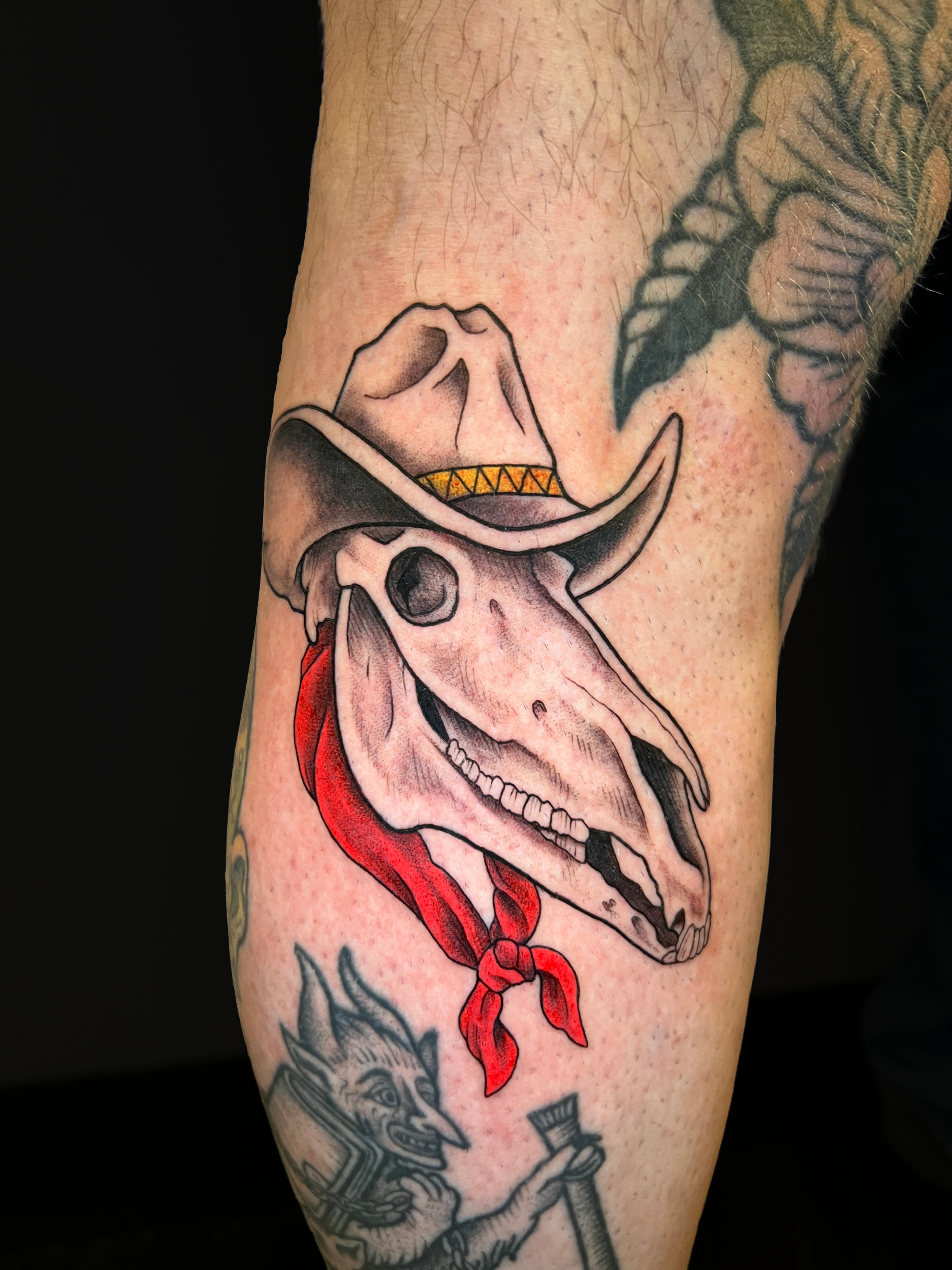 A tattoo of a human skull with a map of the United States inside the skull and a red ribbon hanging from the jaw.