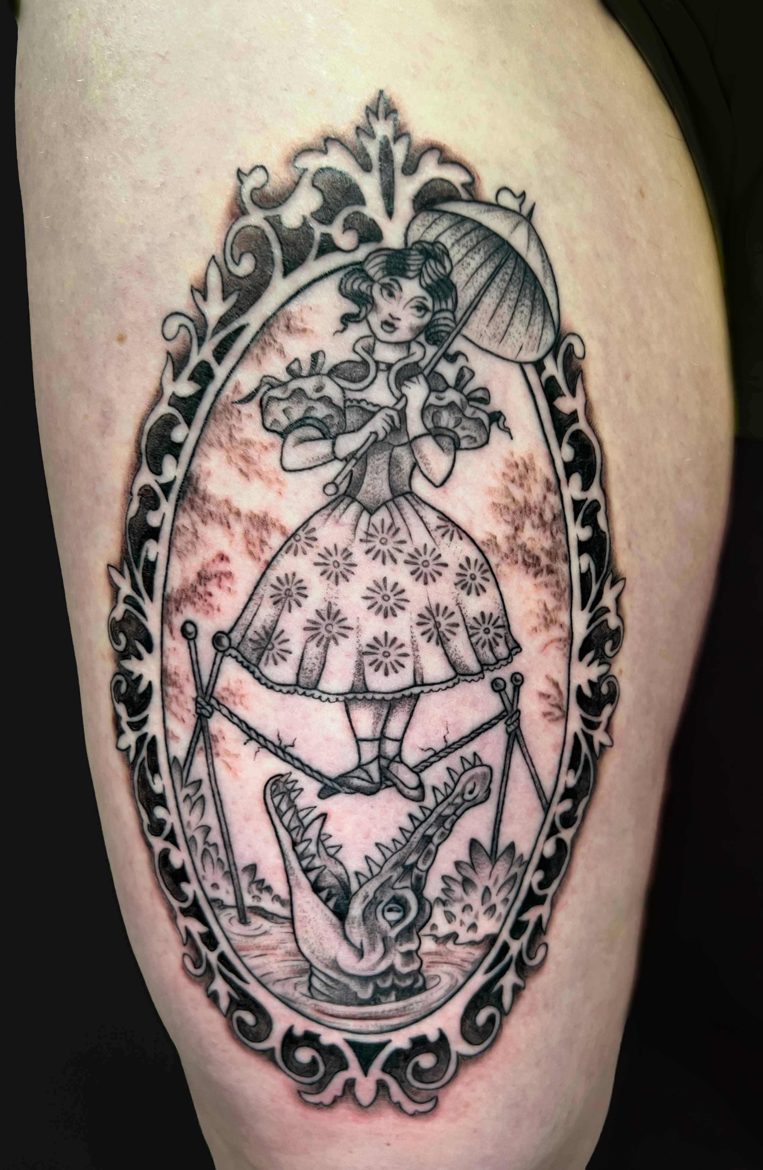 Black and gray tattoo of a princess holding an umbrella, standing on a dragon, enclosed in an ornate arch frame.
