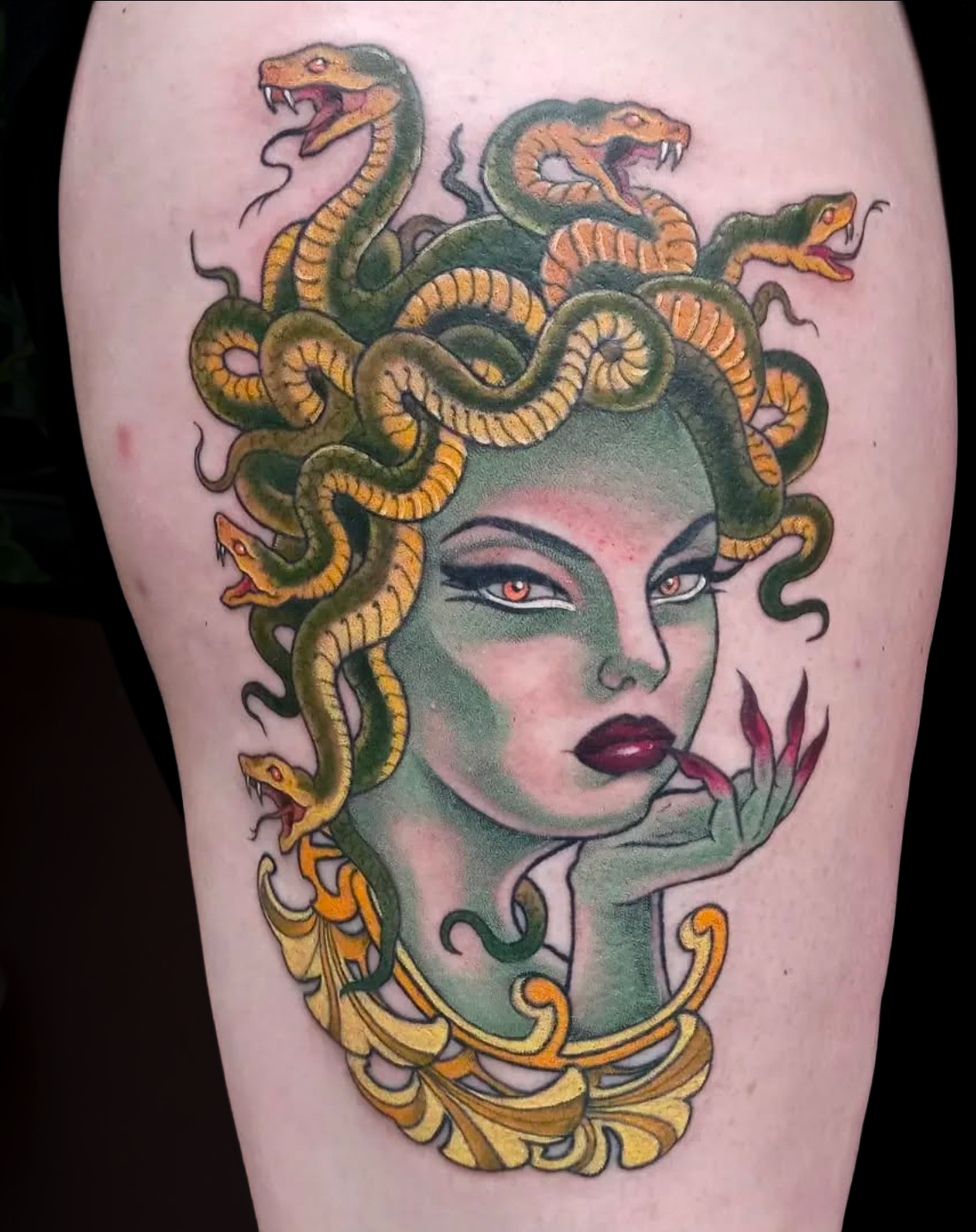 Tattoo of Medusa with snake hair and a woman with red lips and piercing eyes.