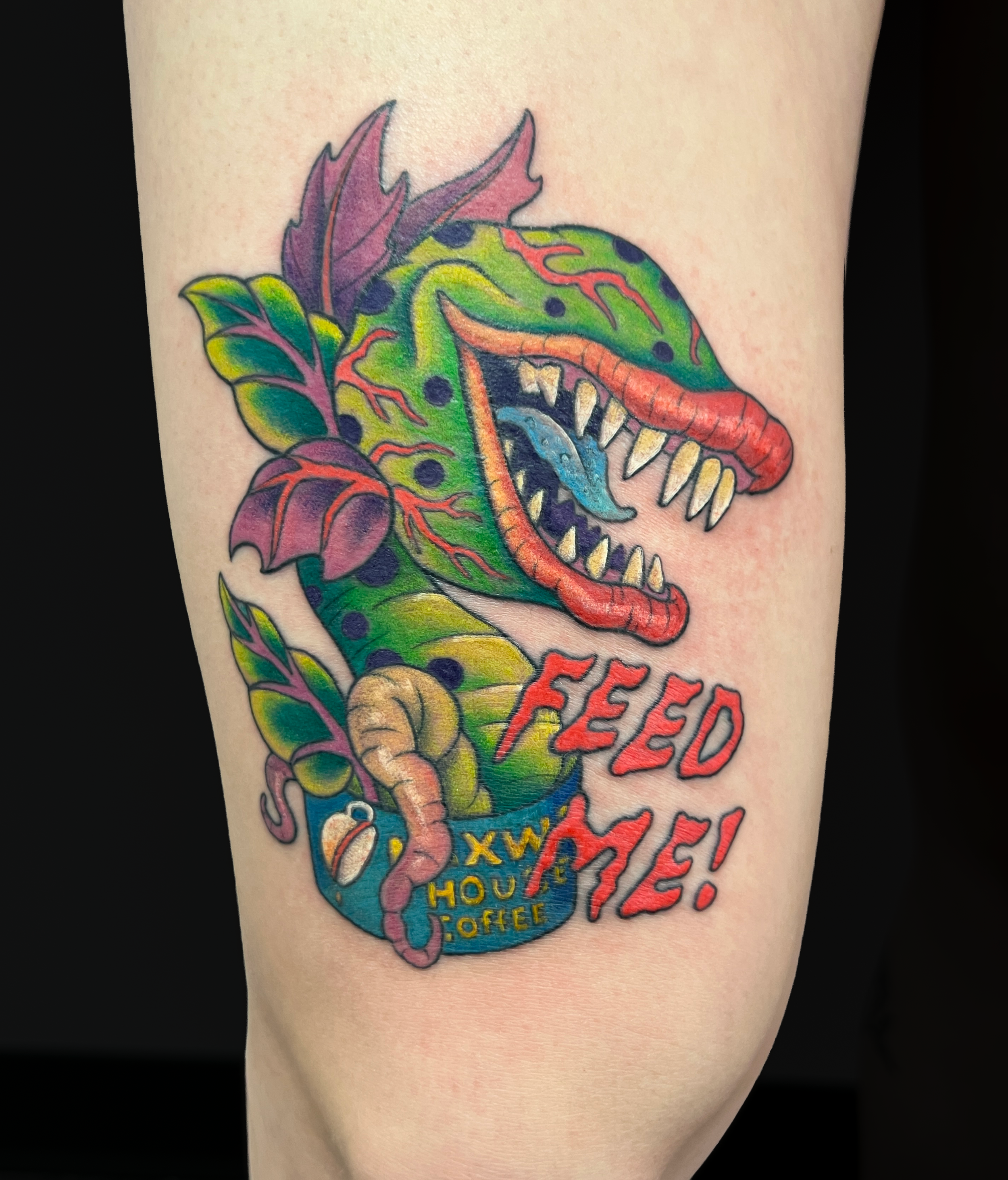 Colorful tattoo of a dinosaur with leafy details and words 'FEED THE HOUSE' on skin.