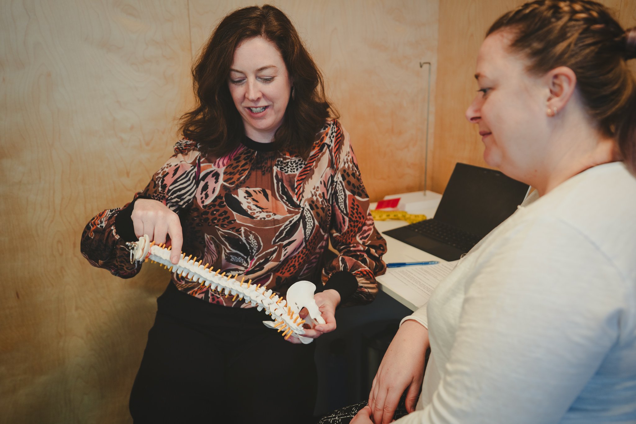 Physiotherapist Marianne Carroll explaining spinal alignment to a client using a spine model during a women's posture and bra fitting consultation in Southland New Zealand