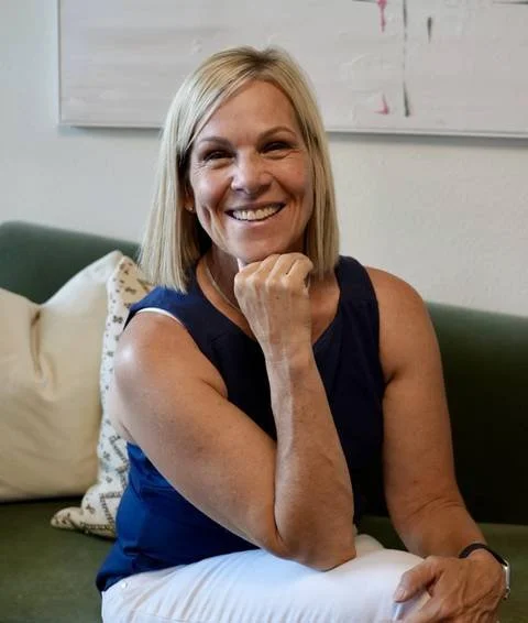 Barbara McGee Strauss seated on a green sofa, smiling