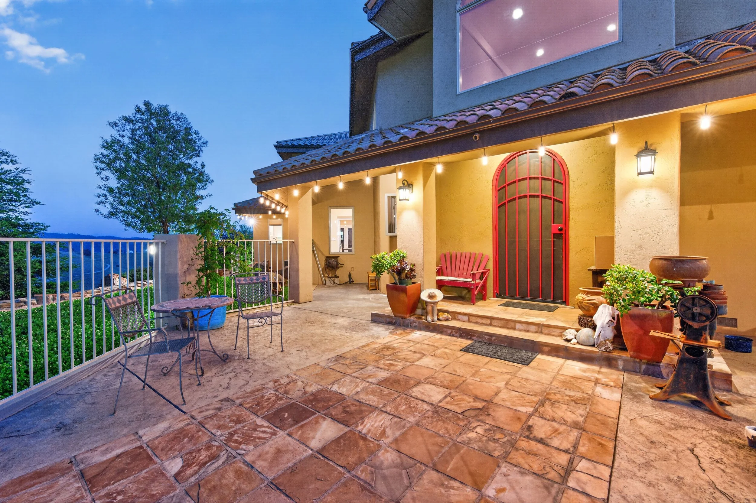 Front entry of the luxury estate at Airola Ranch in Vallecito California featuring warm evening lighting, covered outdoor seating, and inviting Sierra Foothill living spaces