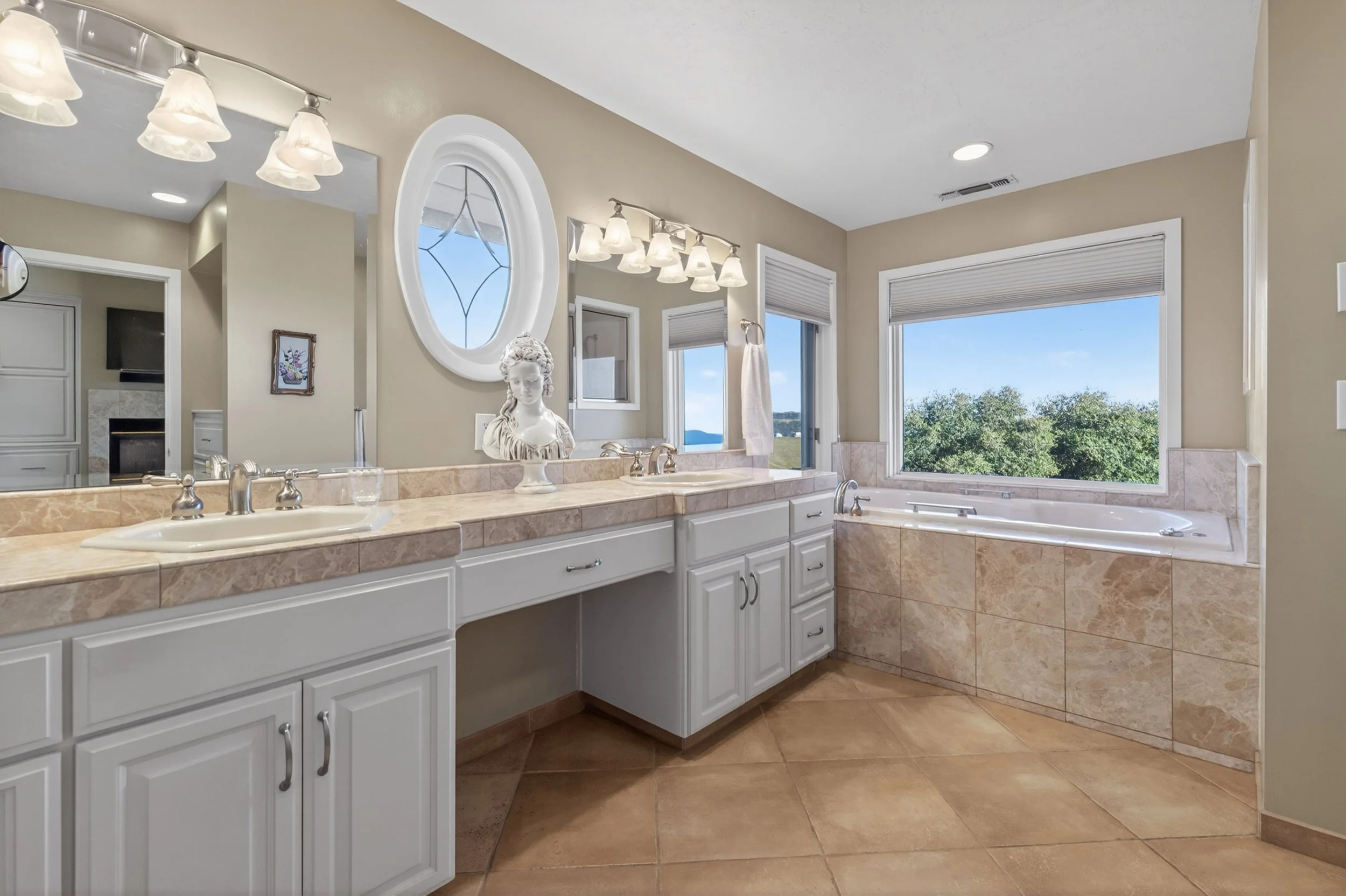 Luxury primary bathroom suite at Airola Ranch in Vallecito California featuring dual vanities, jetted tub, separate shower, natural light, and lake views.