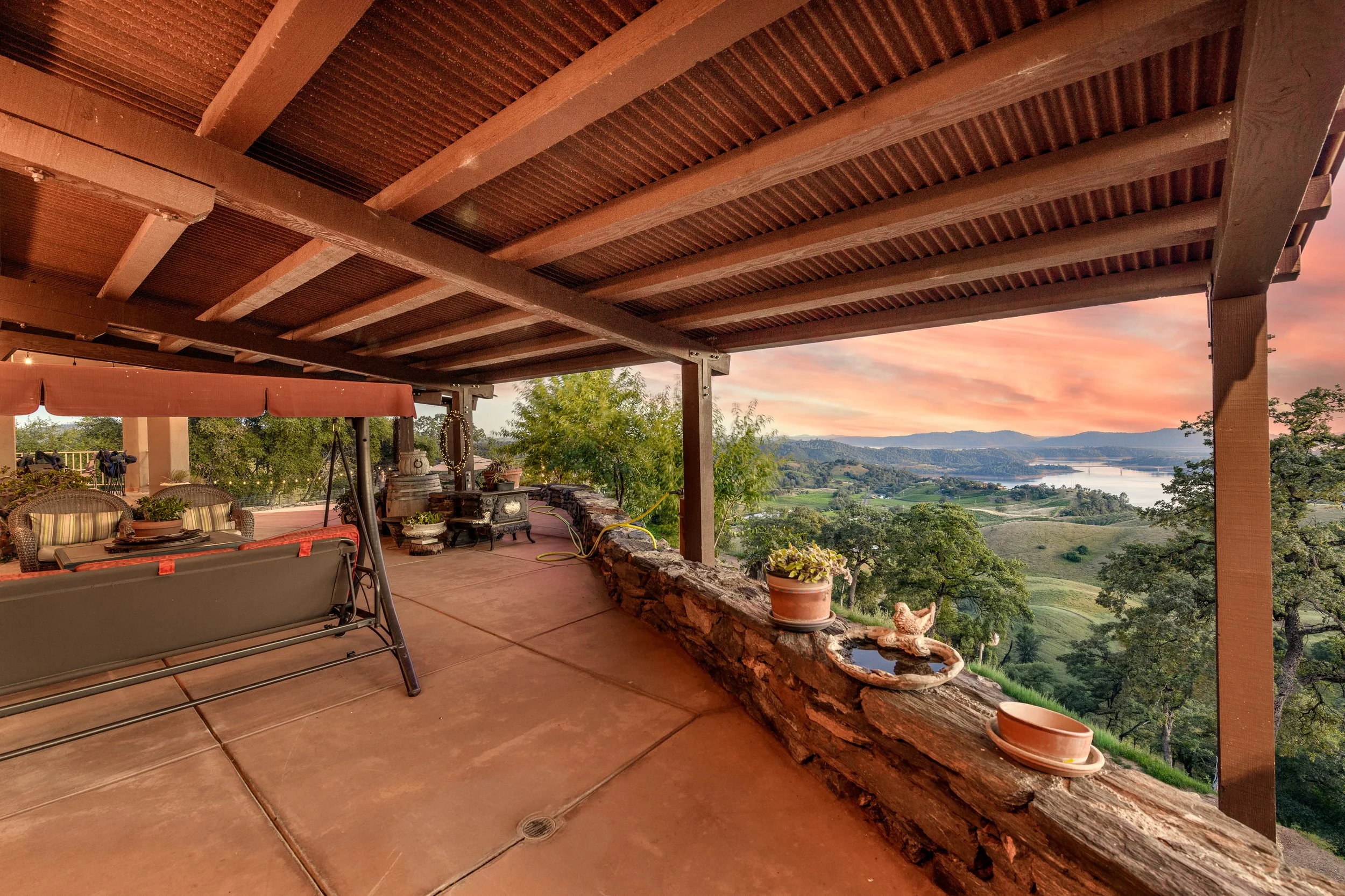 A covered patio with wooden beams and a view of New Melones Lake