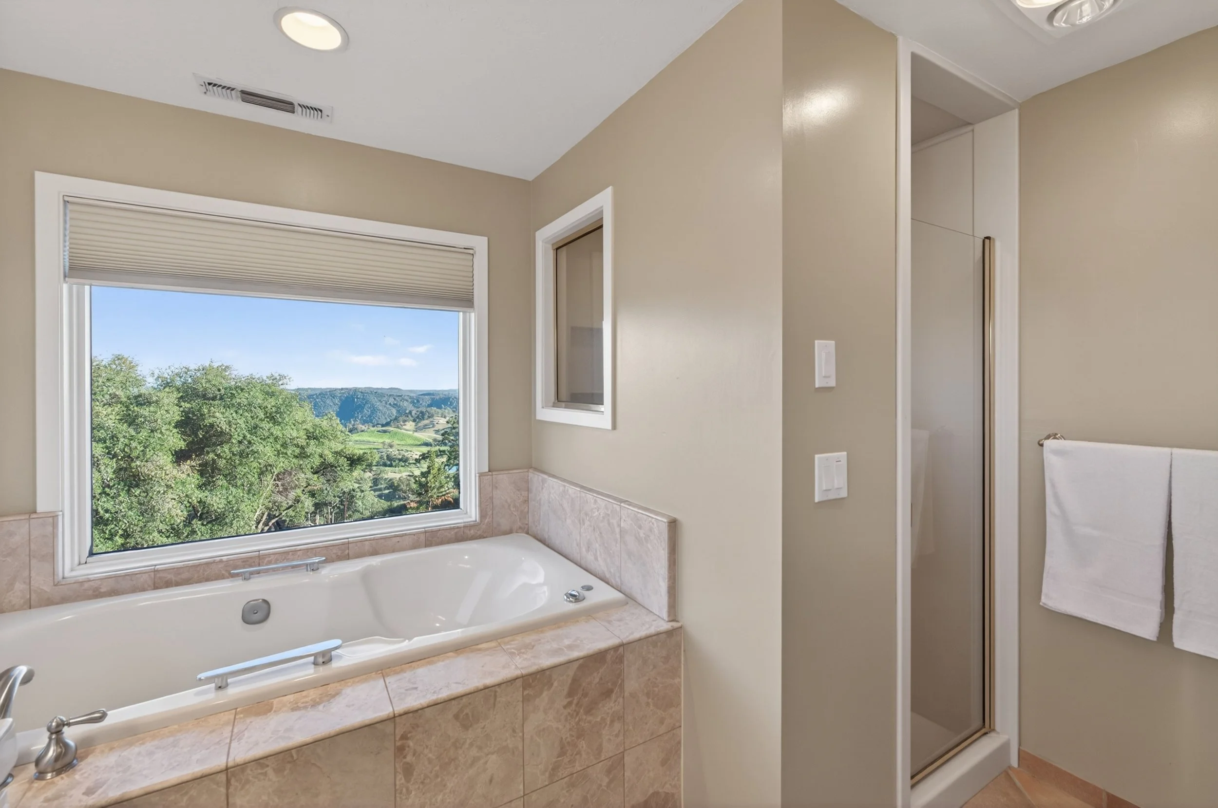Spa-inspired bathroom at Airola Ranch with panoramic hillside views, marble finishes, and glass-enclosed shower.