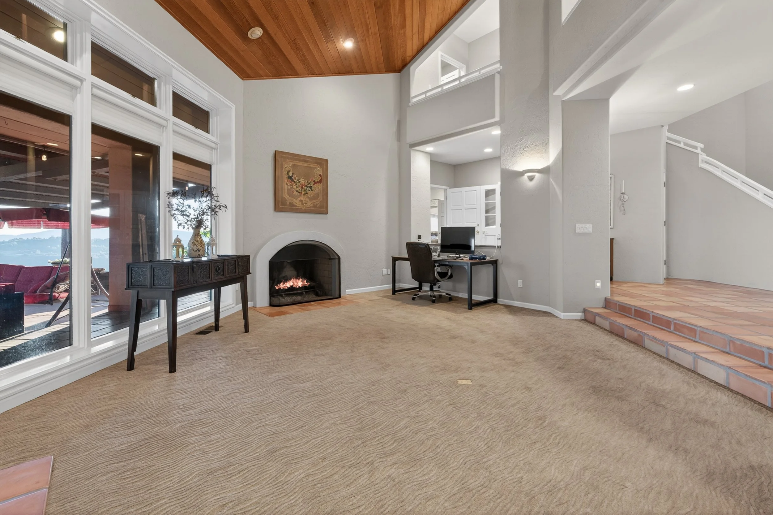 Interior living space at Airola Ranch in Vallecito California featuring a fireplace, large picture windows, and elevated views of the surrounding foothills and New Melones Lake.