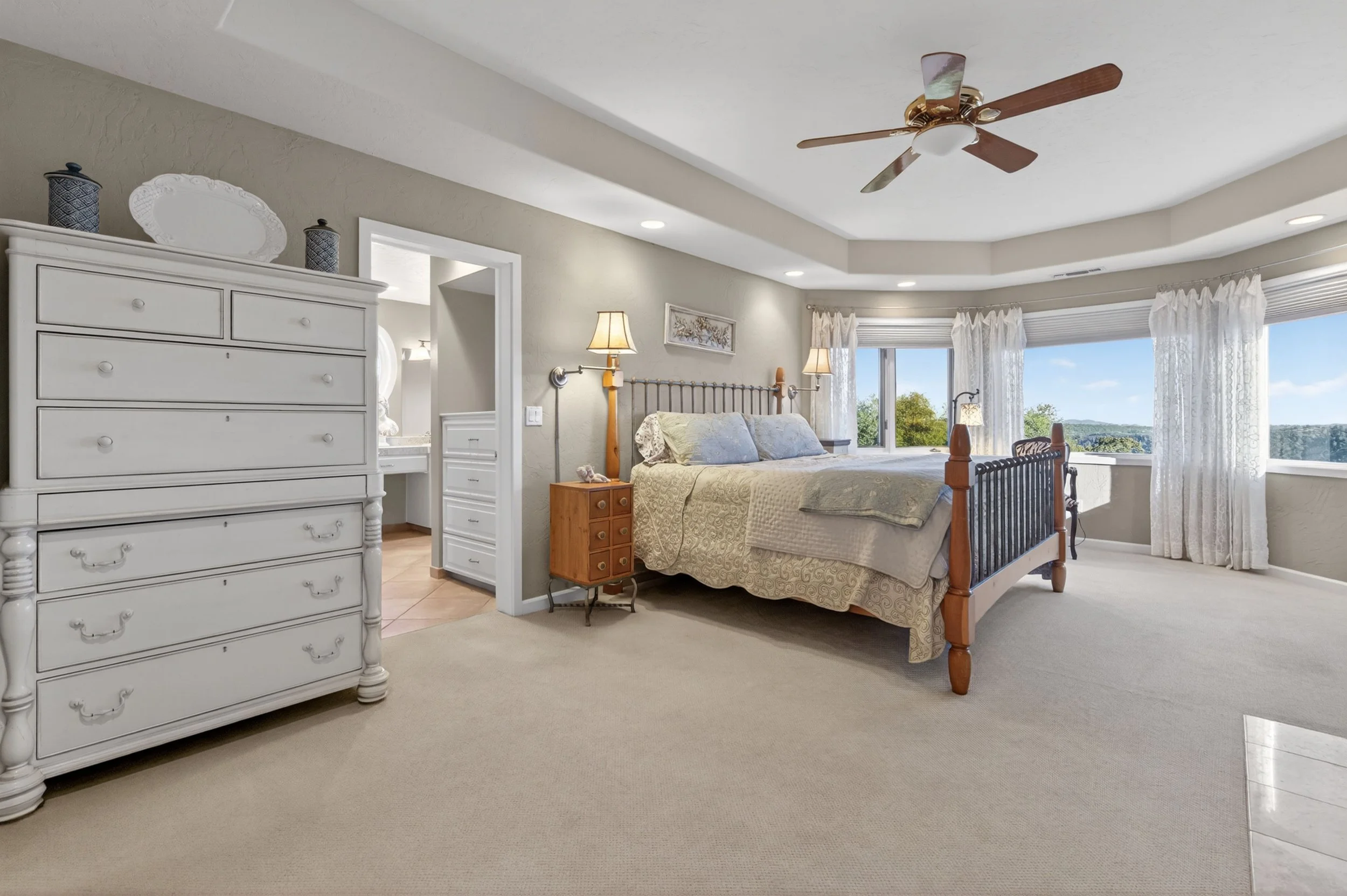 Elegant primary bedroom suite at Airola Ranch with expansive windows, custom finishes, and warm California foothill ambiance and panoramic views of New Melones Lake.