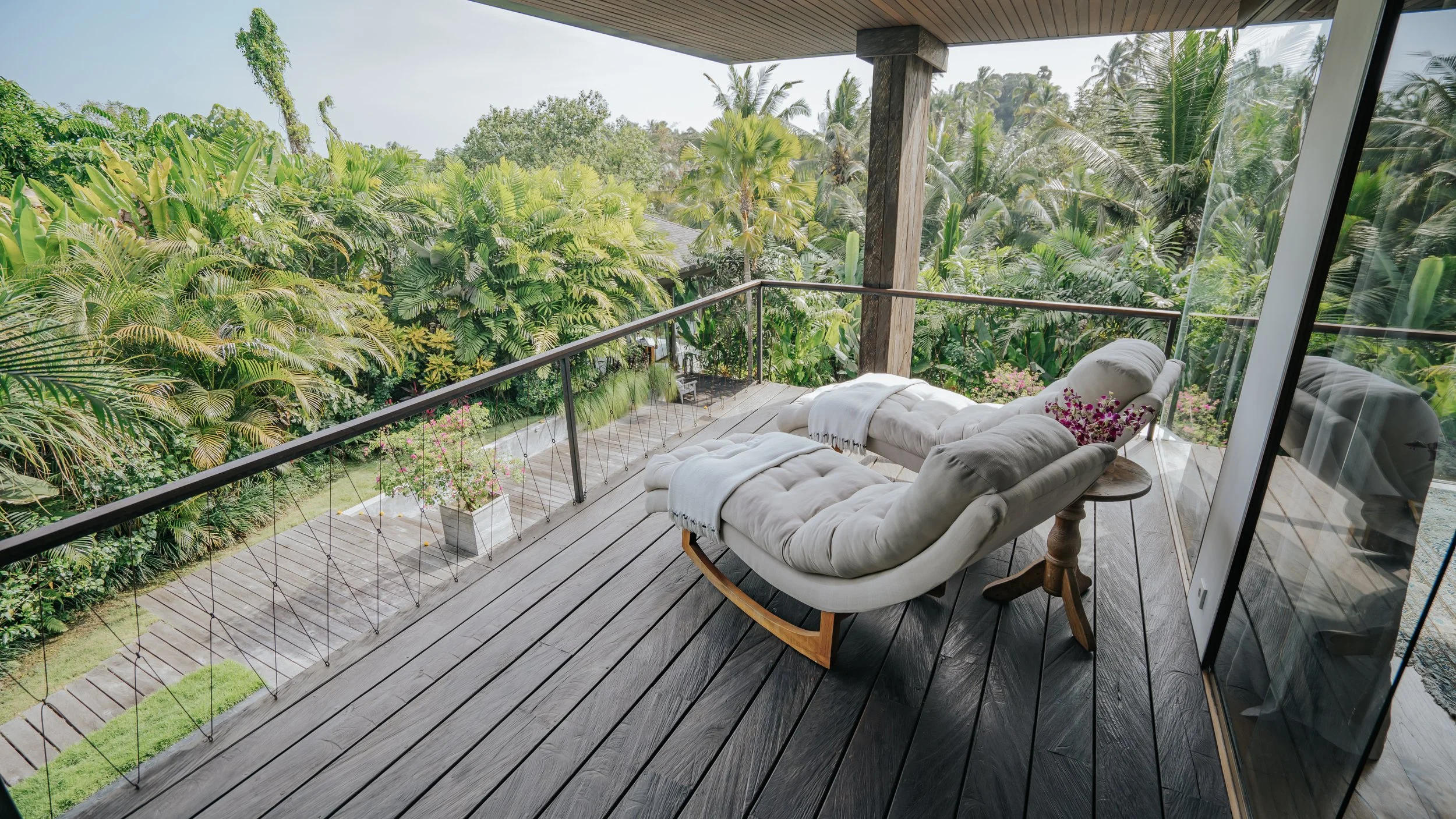 Large private balcony with reclining lazy chairs and a view of the pool and jungle