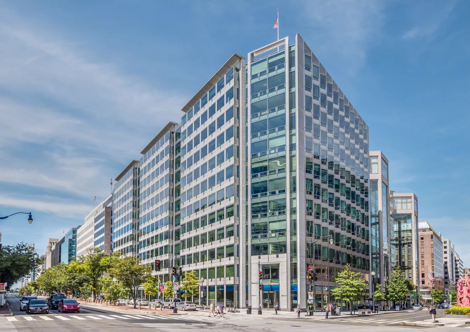 Modern multi-story office building with glass facade, located at 1717 K Street, NW in Washington, D.C. on a busy city street with trees, pedestrians, and cars.