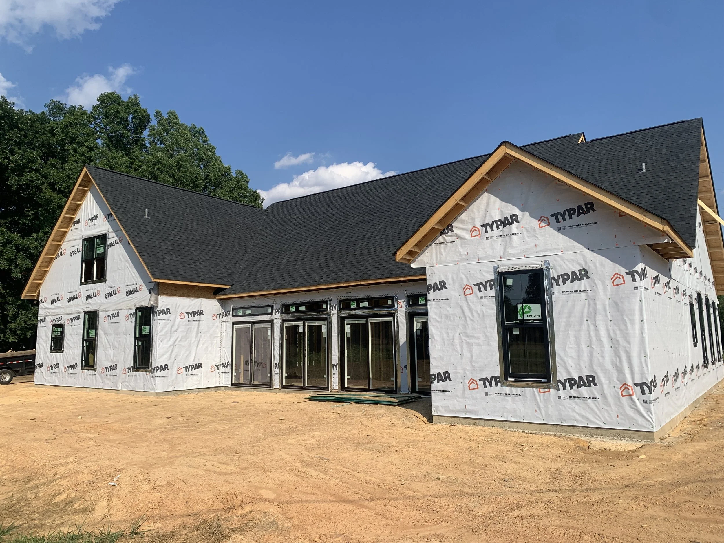 Fully framed residential home with Tyvek exterior, completed roof, windows, and doors installed by McGuirt Carpentry & Construction
