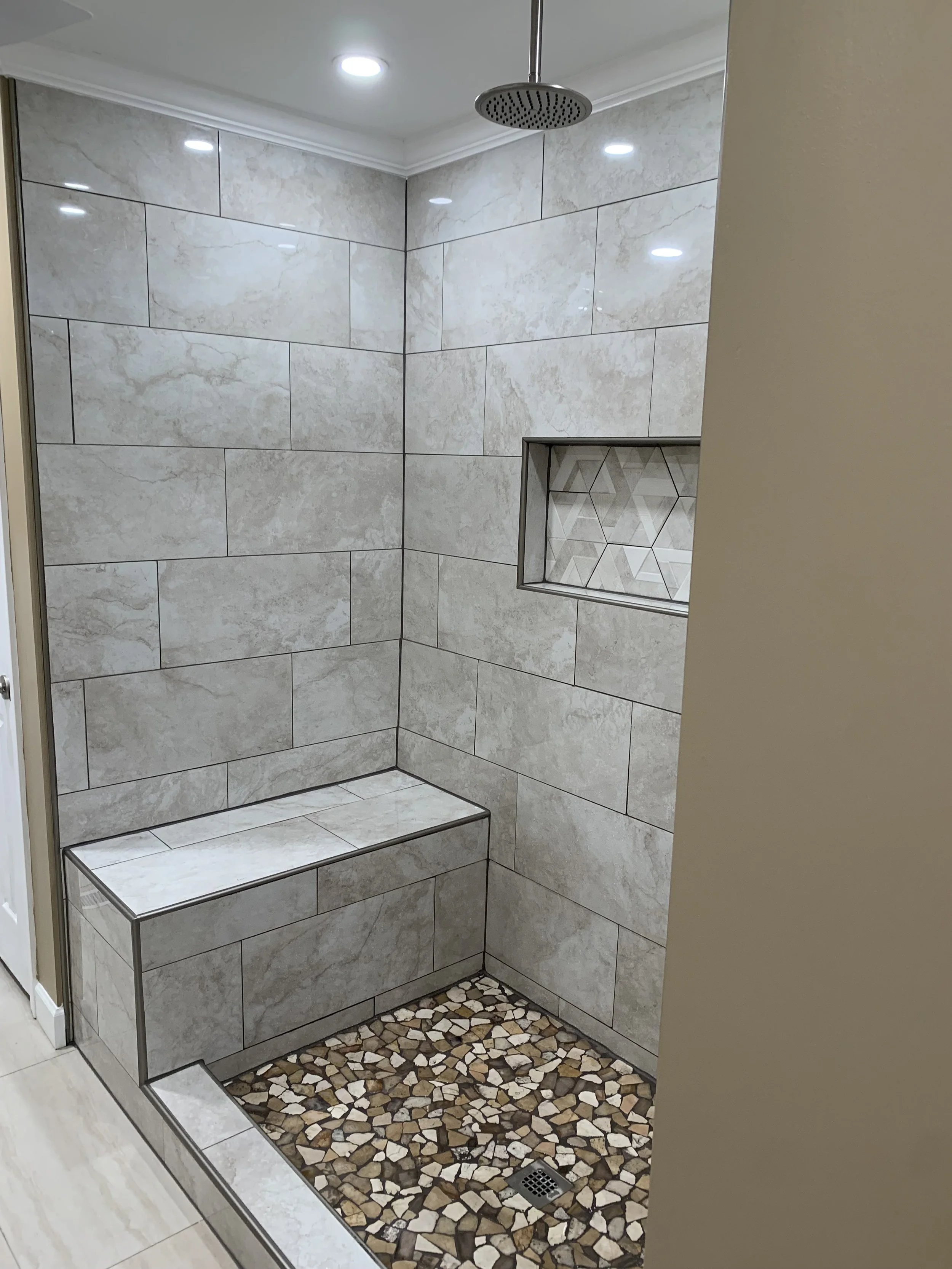 Bathroom remodel in Lancaster, SC featuring a tiled walk-in shower with built-in bench, shower niche, and rainfall showerhead.