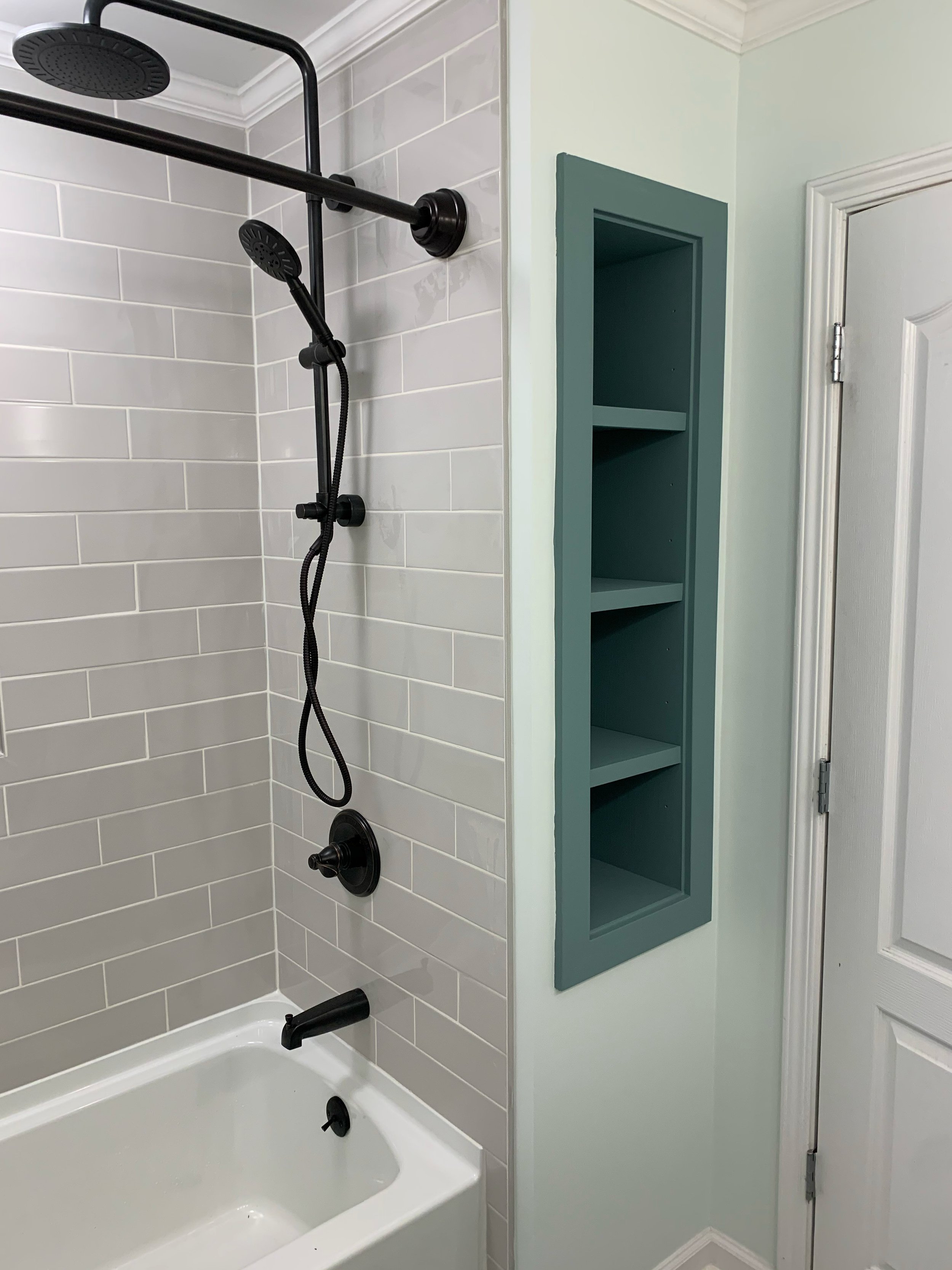 Bathroom tub and subway tile shower remodel featuring matte black fixtures and custom built-in shelving in Lancaster, SC.