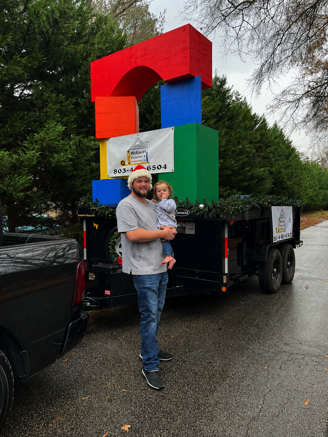 Randall McGuirt with his son Bennett beside the McGuirt Carpentry & Construction Christmas parade display.