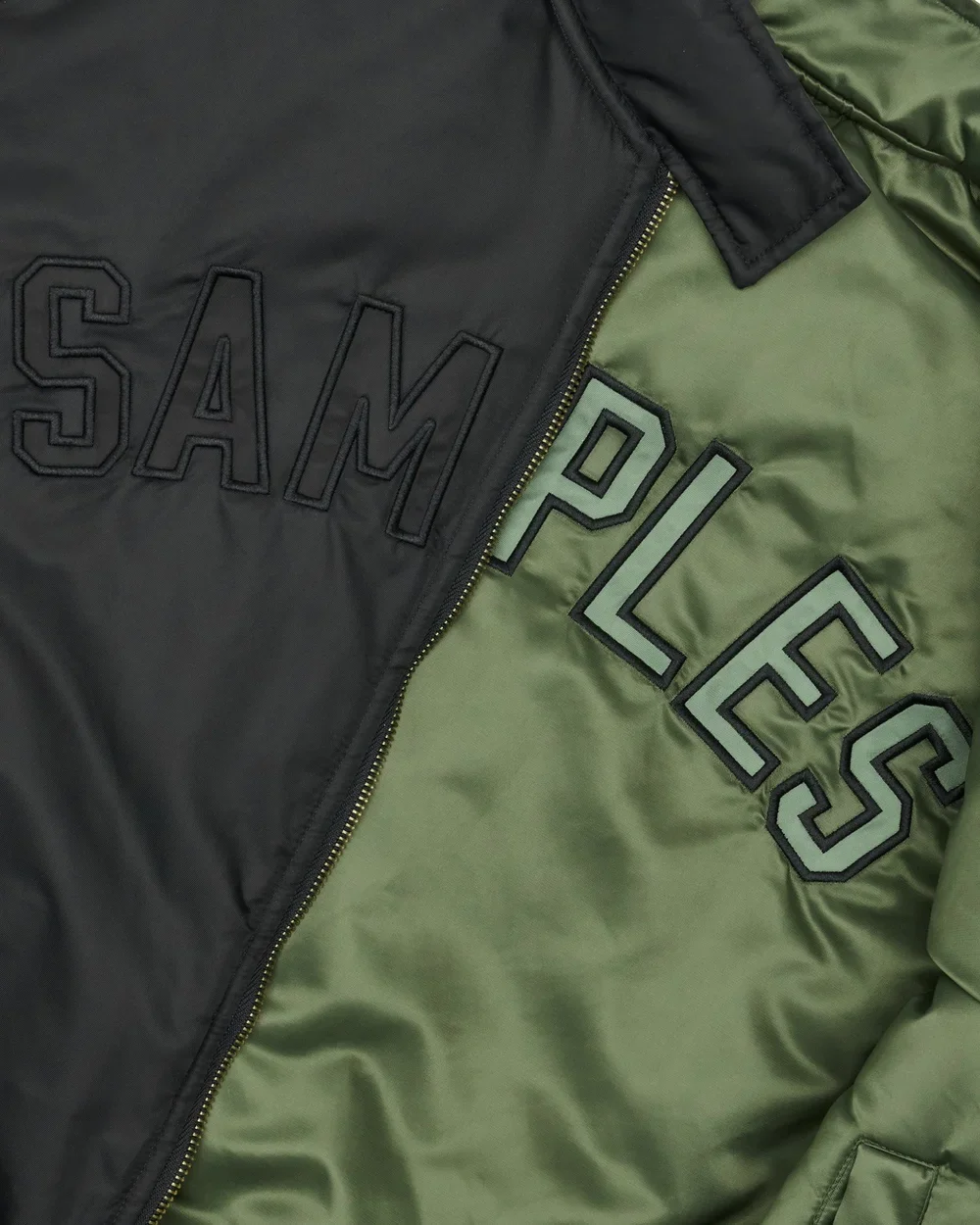Close-up of a black and green jacket with embroidered patches reading "SAM" and "POLICE."