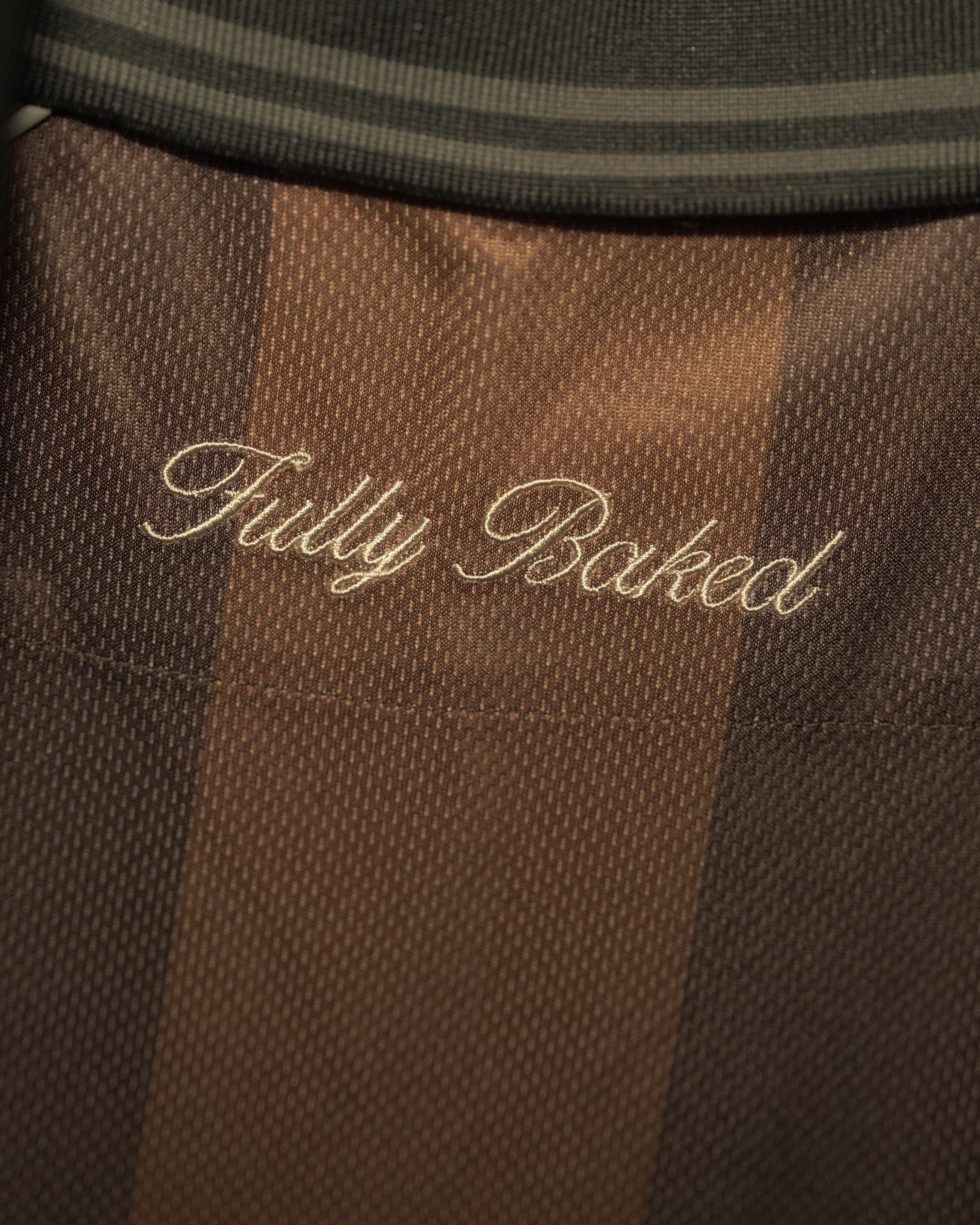 Close-up of a brown fabric bag with the words "Fuddy Backpack" embroidered in cursive white thread.