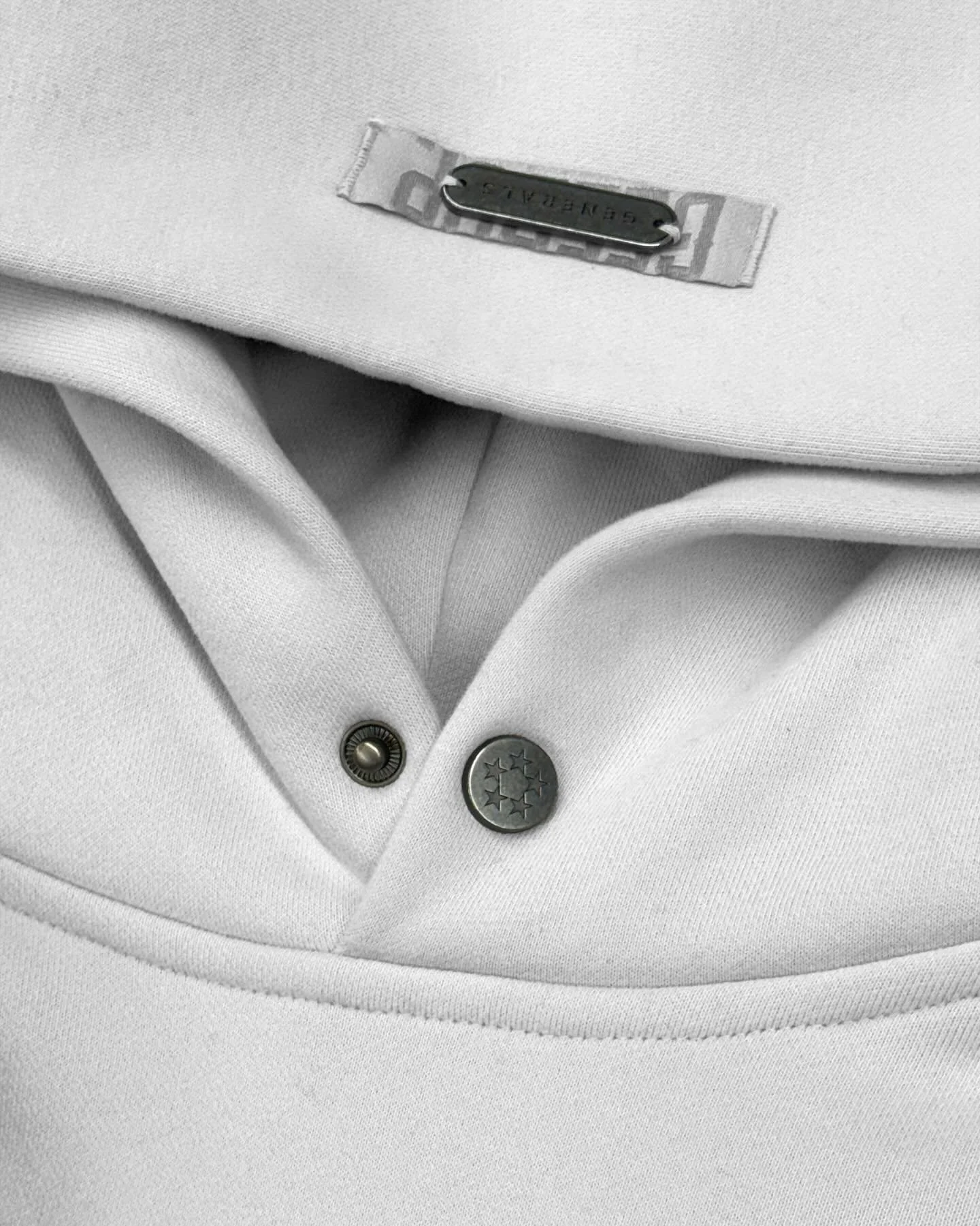 Close-up of a white collared shirt with metal buttons and a label on the collar.
