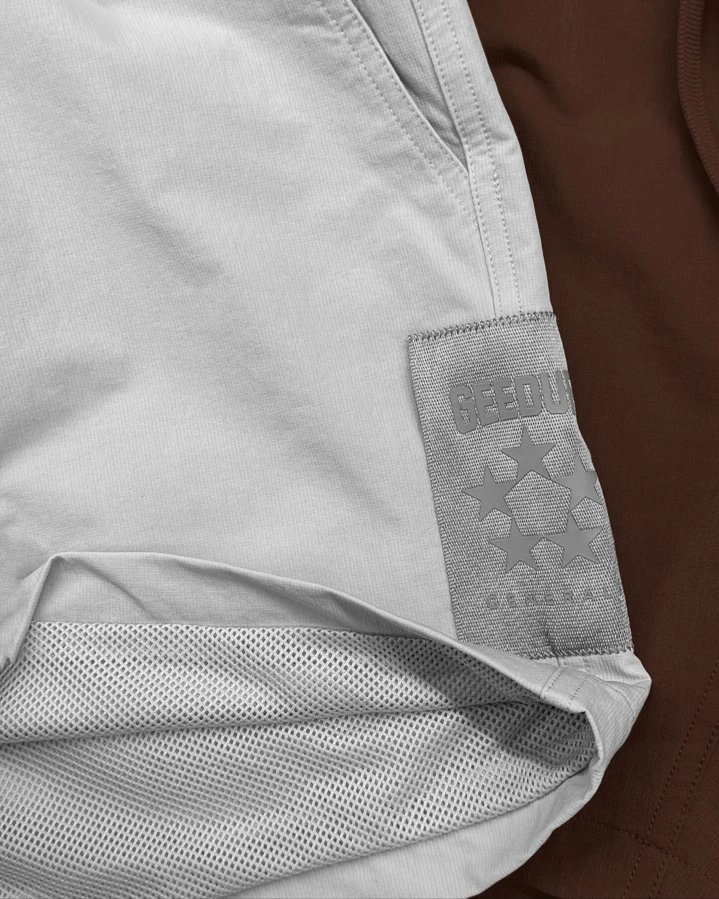 Close-up of a white sports jersey with gray sewn-on patches, one reading "GEO" and displaying a cluster of stars, resting on a brown leather surface.