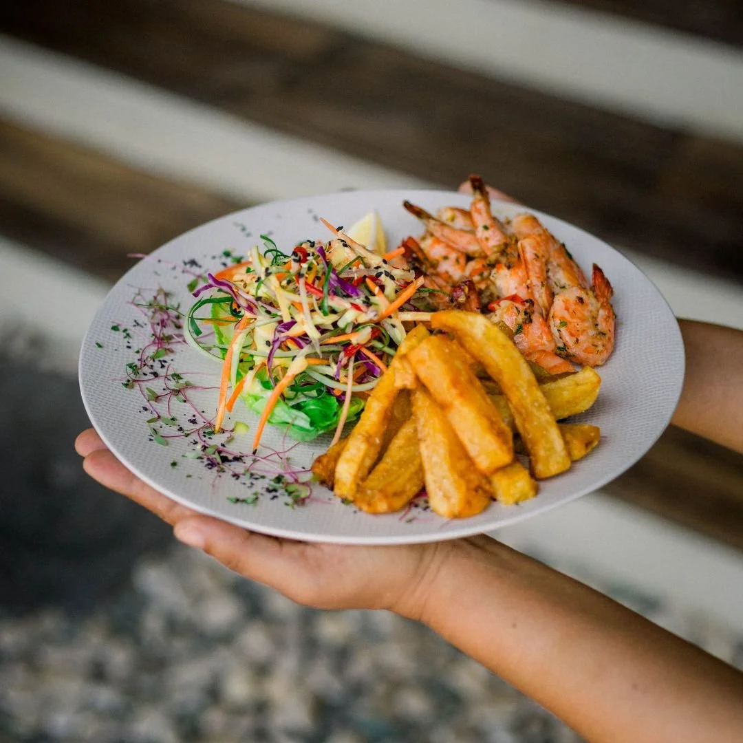 Plate of grilled shrimp, fried yuca, and a side salad with shredded vegetables and microgreens