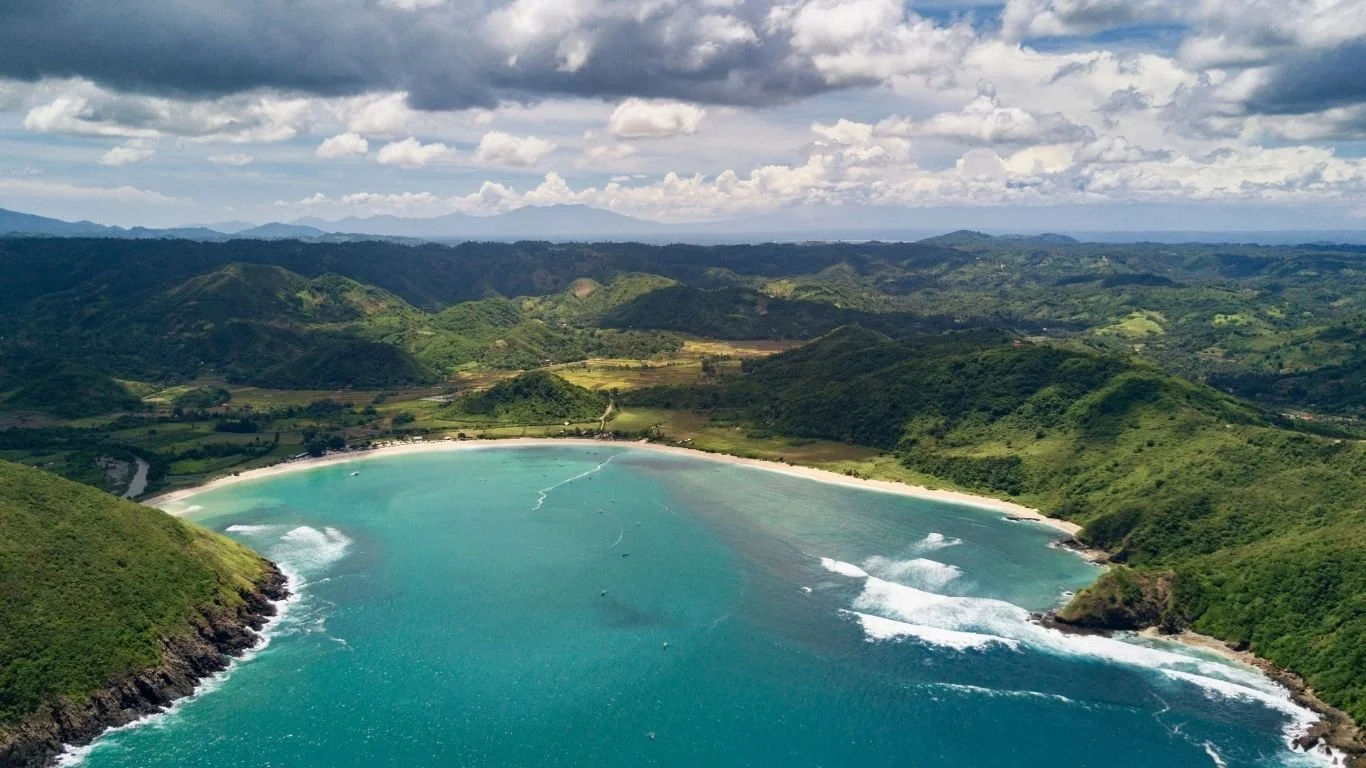 Panoramic aerial view of Mawun Beach with turquoise water and surrounding green hills in Lombok.