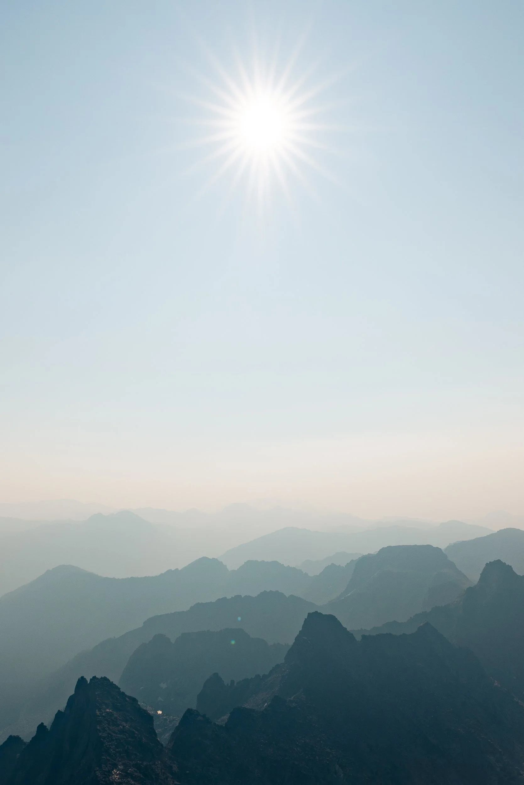 Mountains under a clear sky with the sun shining brightly.
