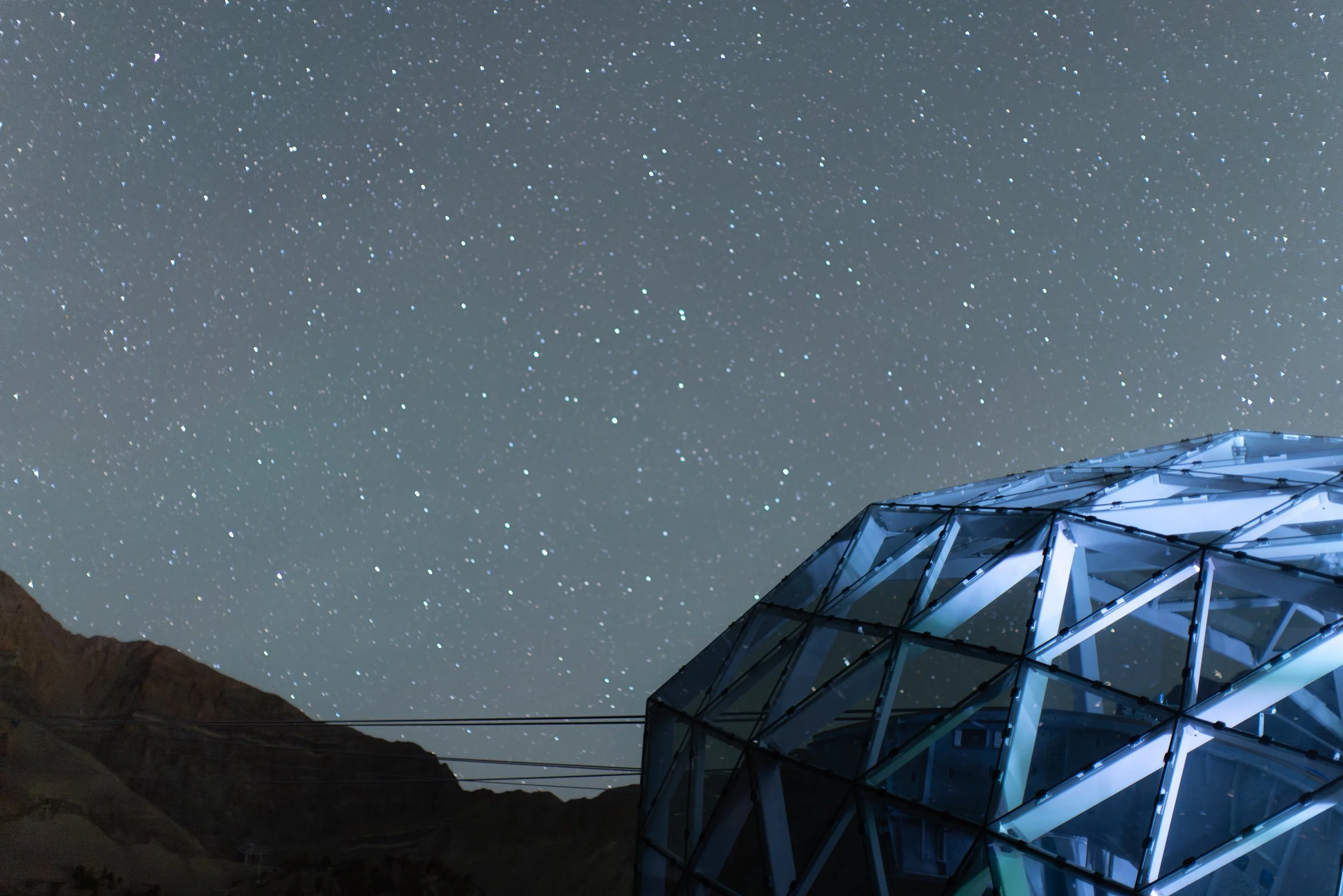 Night sky filled with stars above a modern glass building with a geometric design.