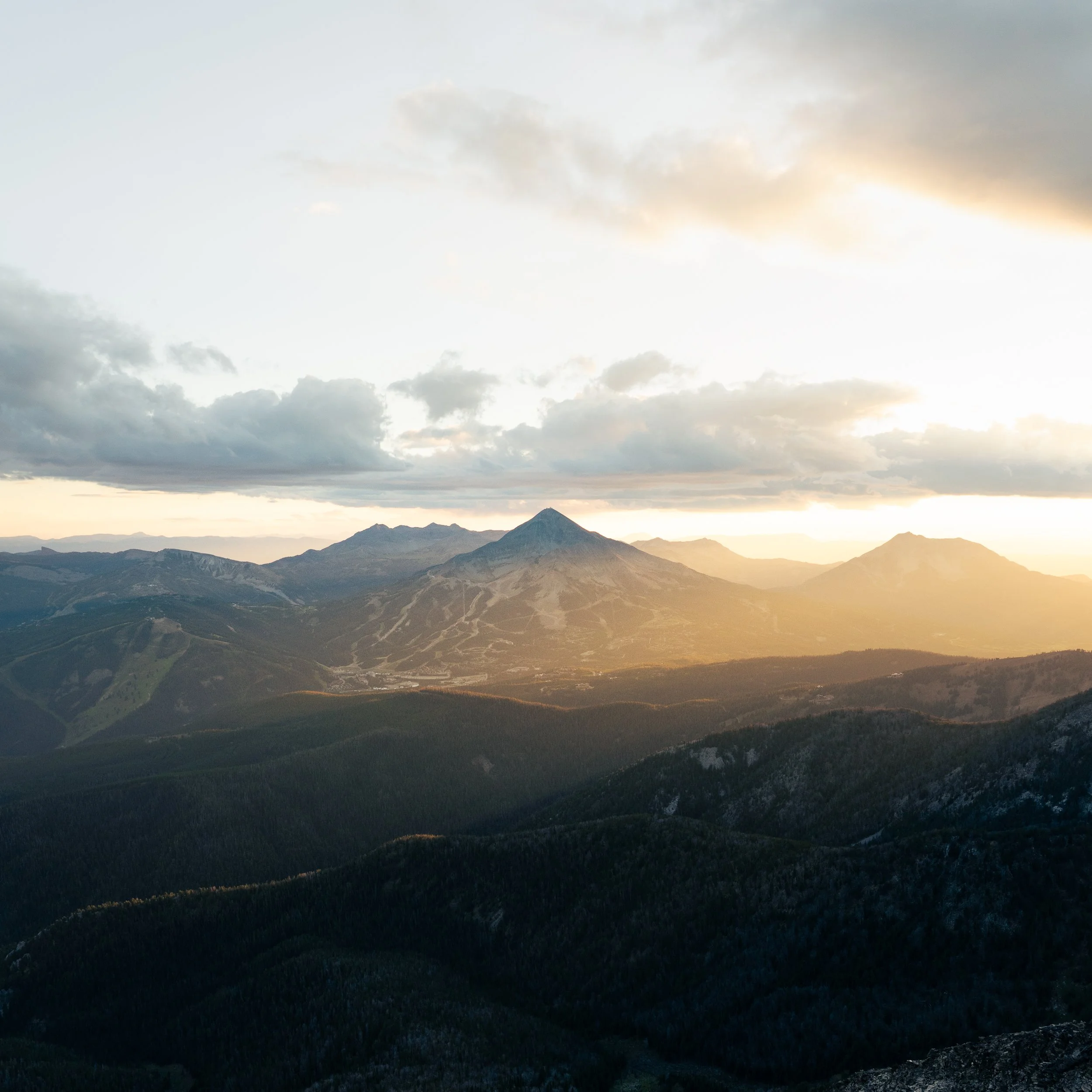 A scenic view of a mountain range under a sky with scattered clouds during sunset or sunrise.
