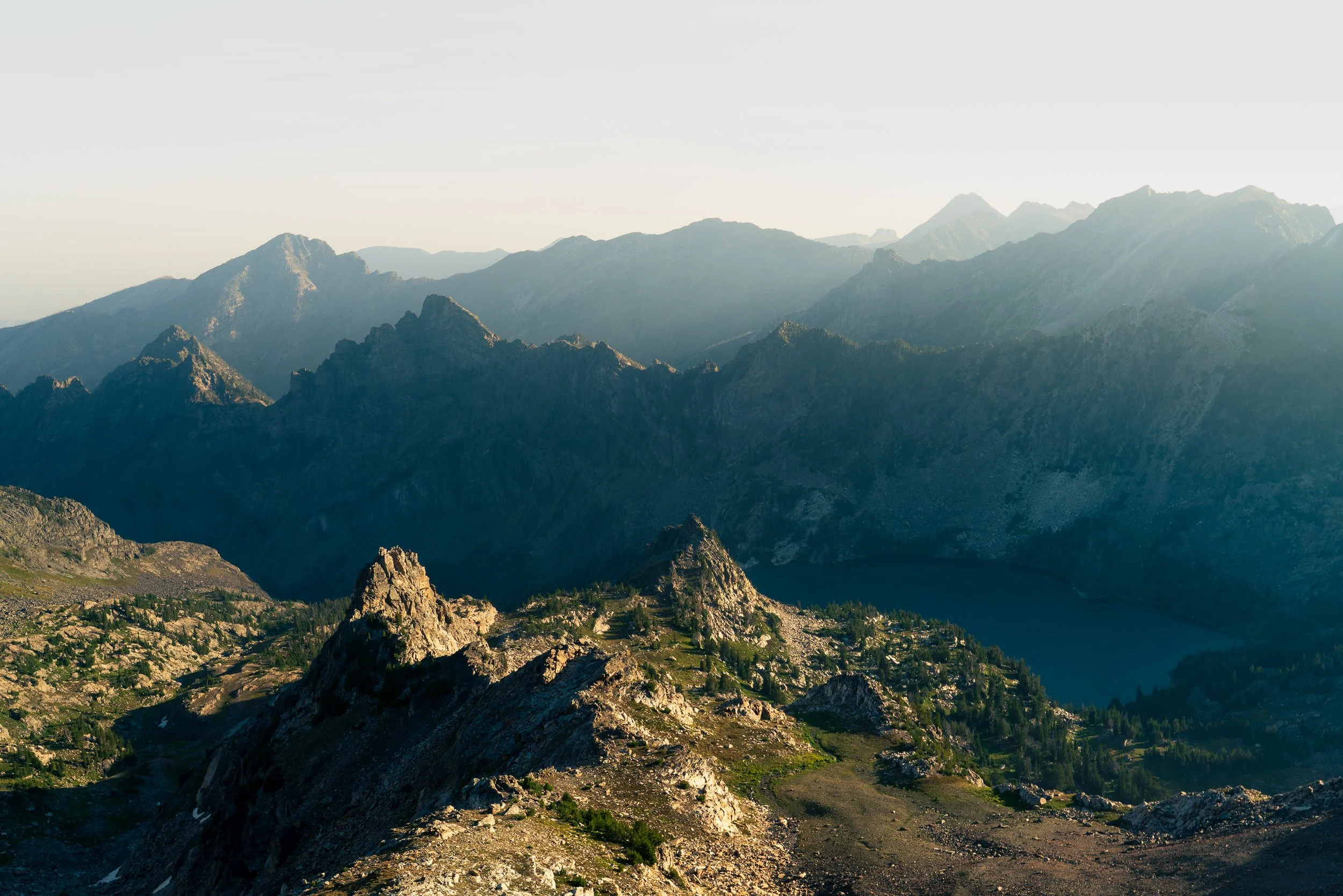 Mountain range with rugged peaks and green valleys, under a clear sky.