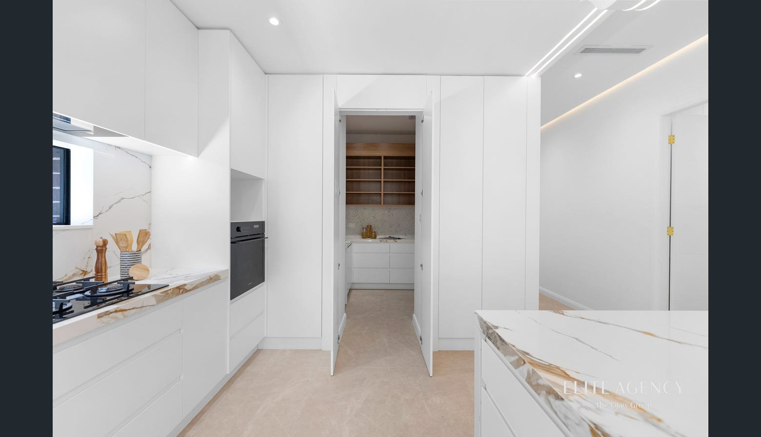 Modern kitchen with white cabinets, marble countertops, built-in oven, gas stove, and small window, minimalist design with recessed lighting.