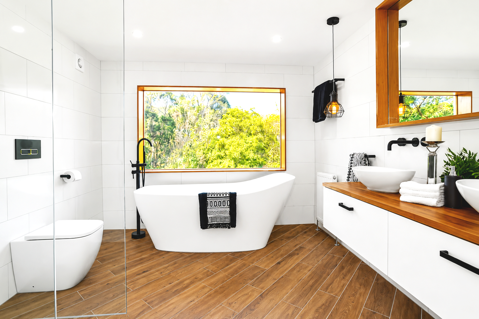 Modern bathroom with a white bathtub, a large window showing green trees, a white toilet, black fixtures, and a wooden vanity with vessel sinks and plants.