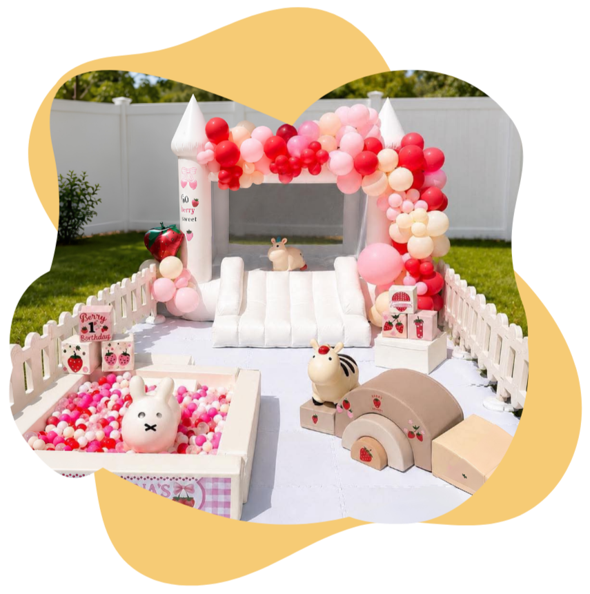 Decorated outdoor space with a white picket fence, pink and red balloons, and plush animal toys, including a bunny and a sheep, for a child's birthday celebration with strawberry-themed decorations.
