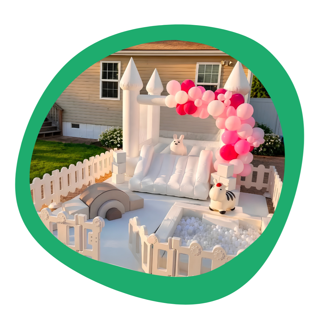 Inflatable white castle with pink balloons, bunny and zebra toys, small fenced play area, and a house in the background.